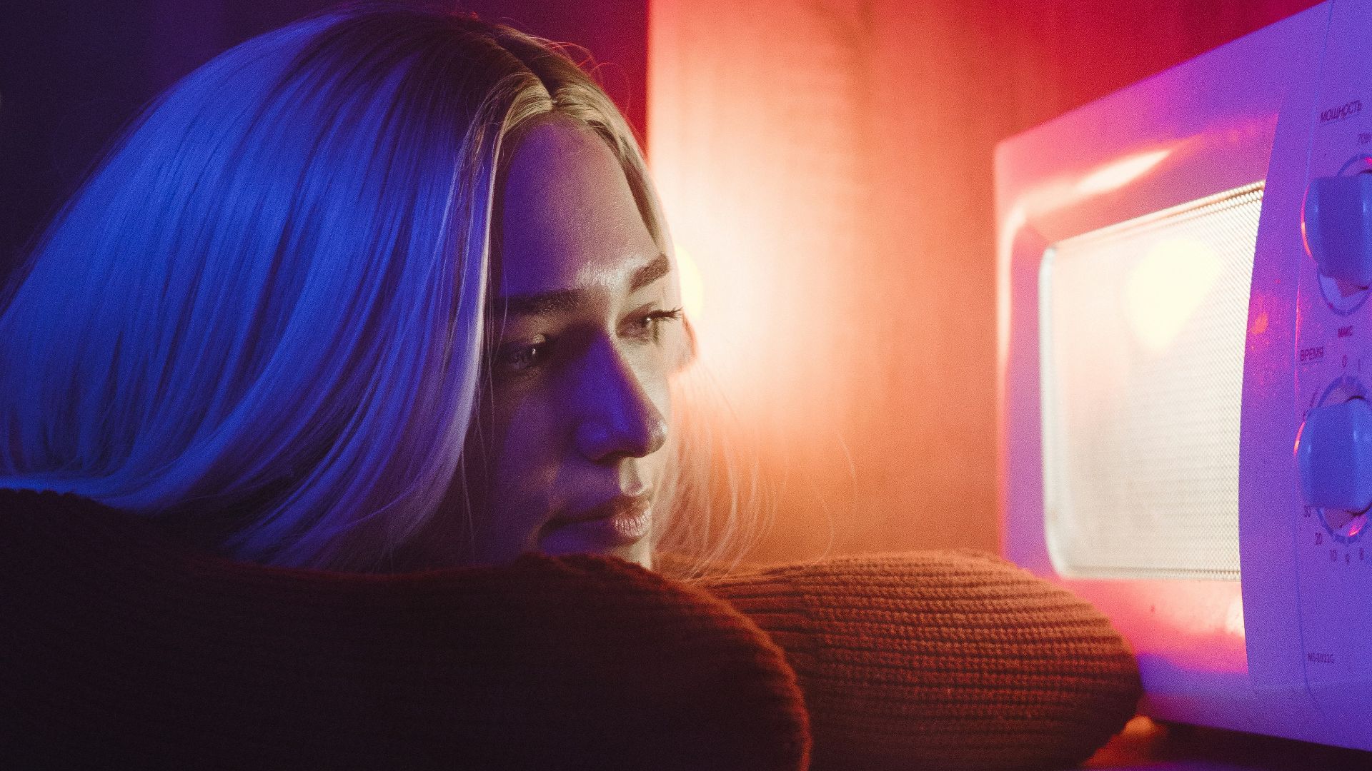 woman in black long sleeve shirt sitting beside white microwave oven