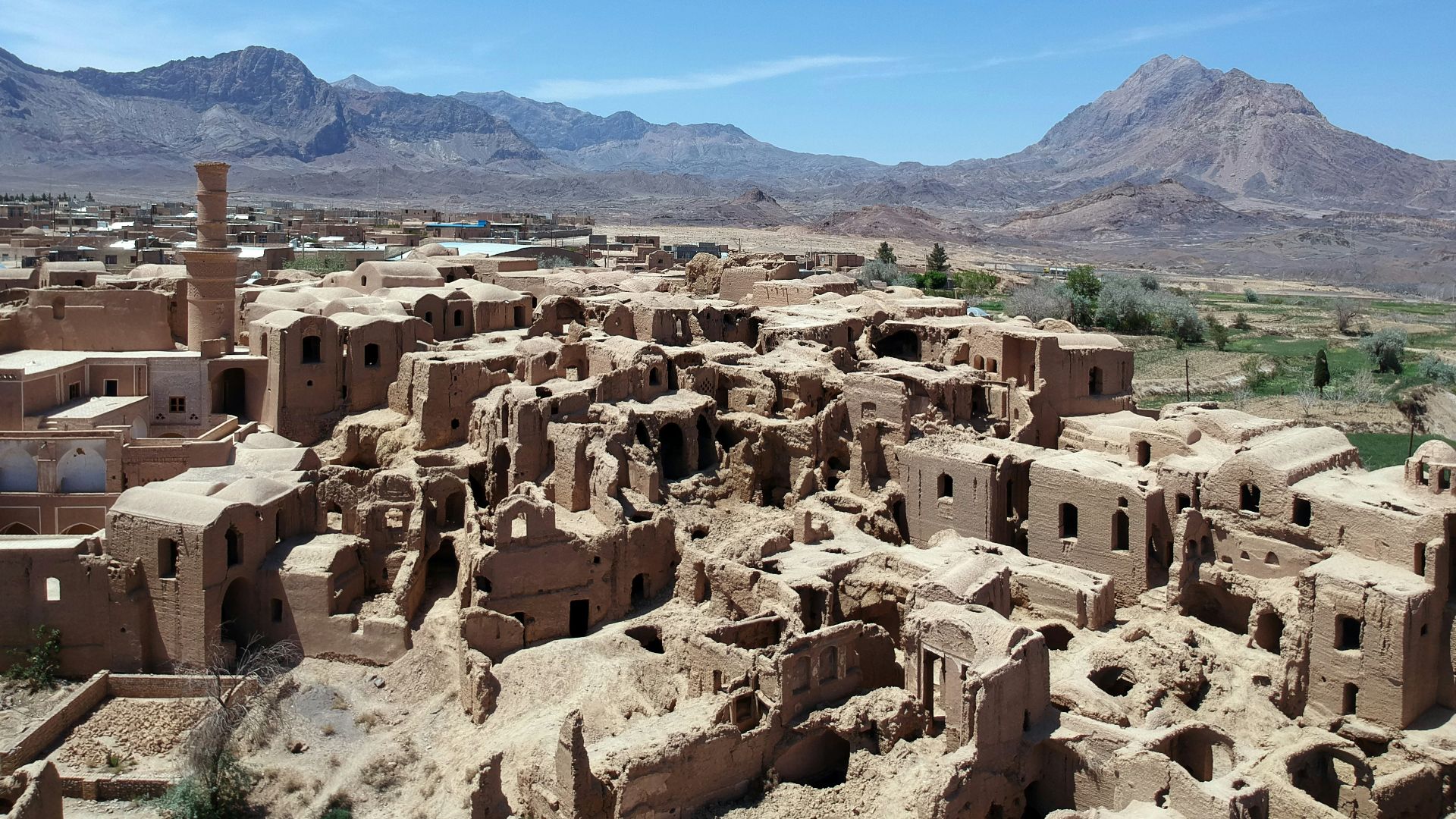 a village in the middle of a desert with mountains in the background