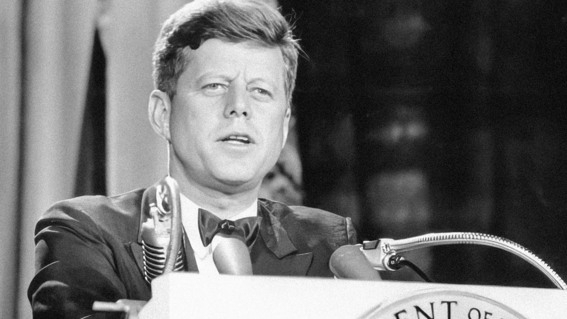 a man in a suit and tie standing at a podium