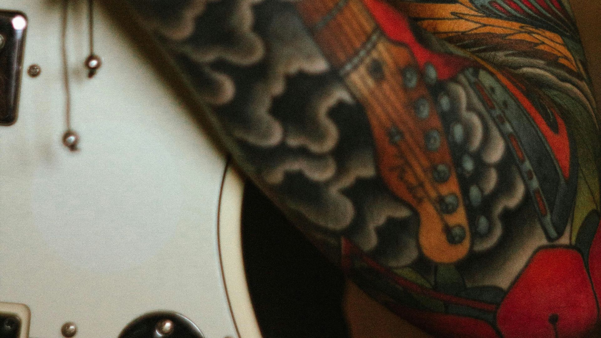 a man with a tattoo on his arm holding a guitar