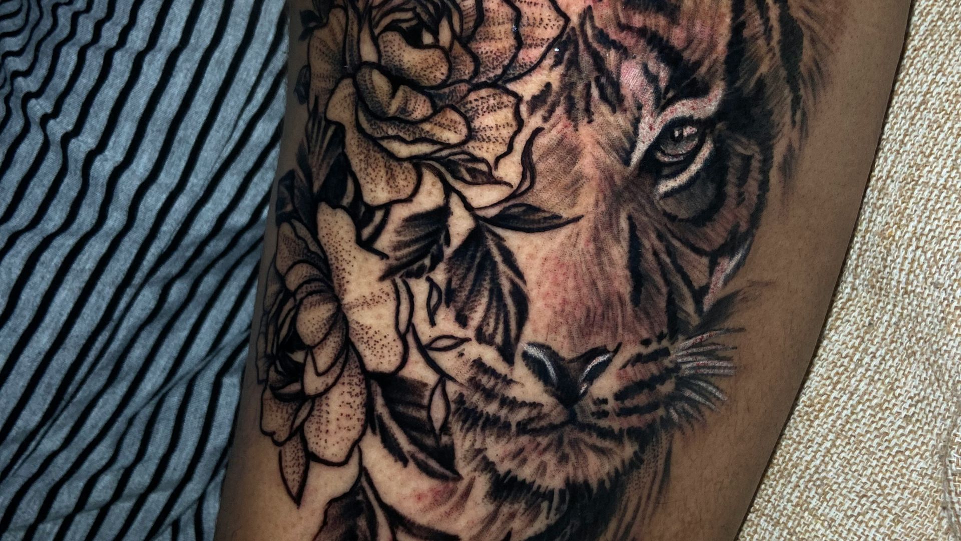 a tattoo of a tiger and flowers on a woman's thigh