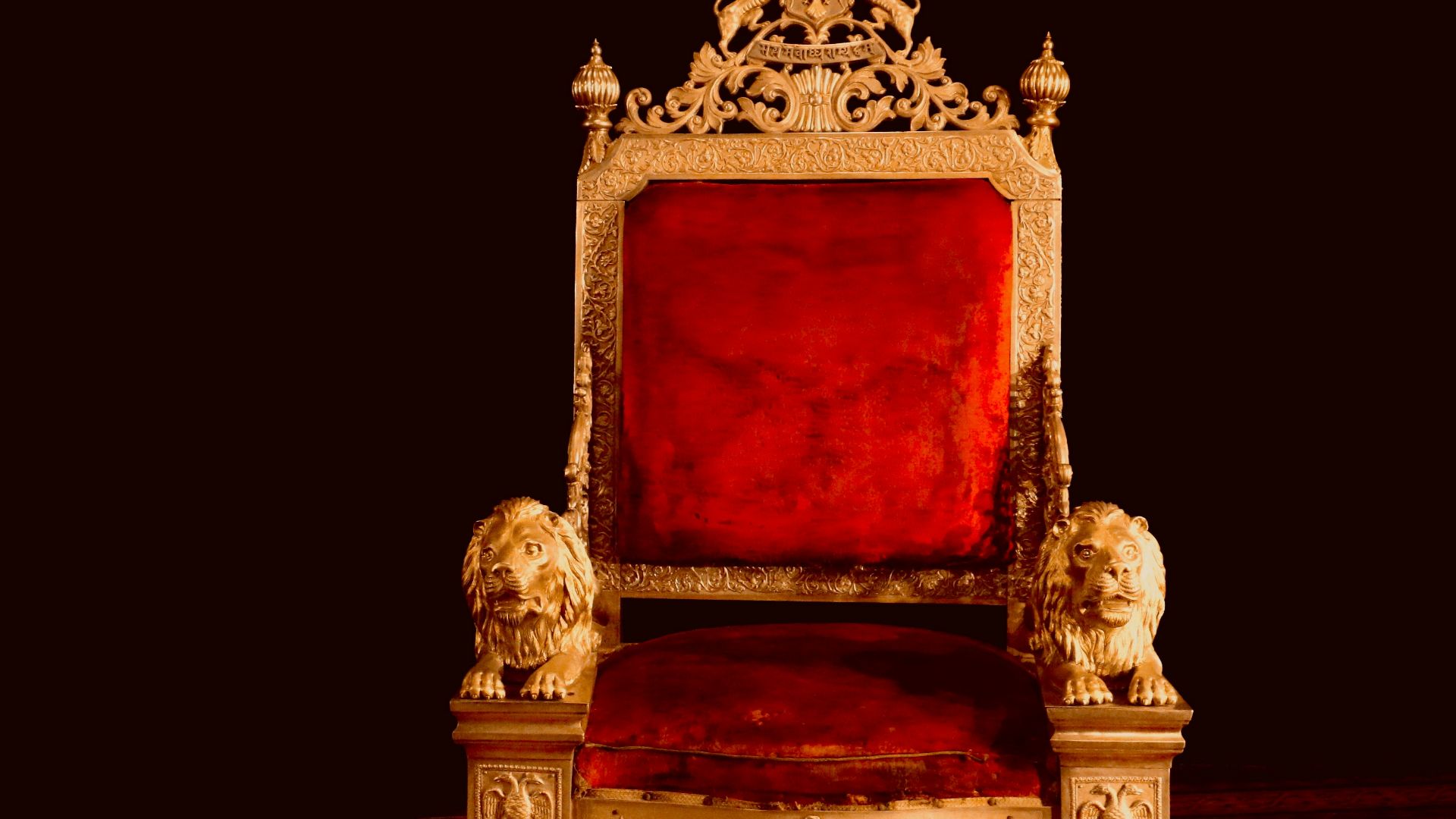 A gold and red chair sitting on top of a wooden floor
