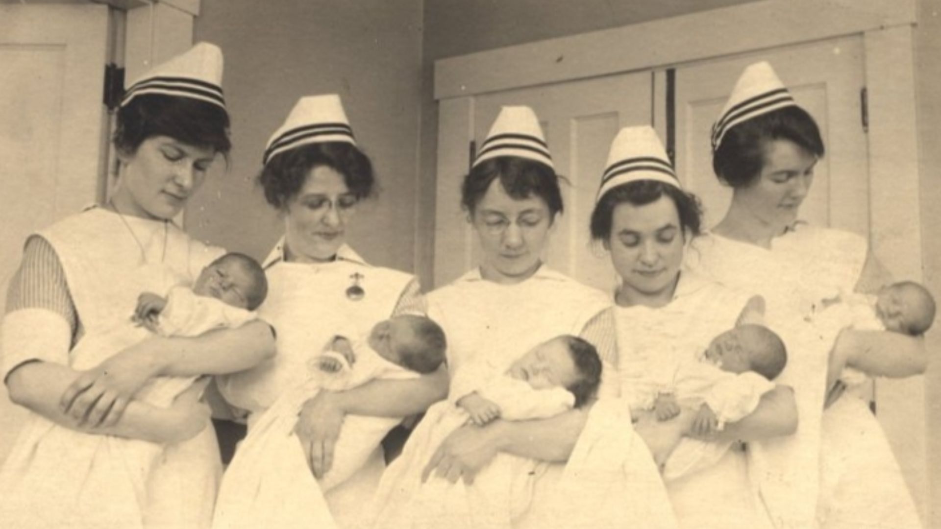 File:Five nurses each holding a baby..JPG