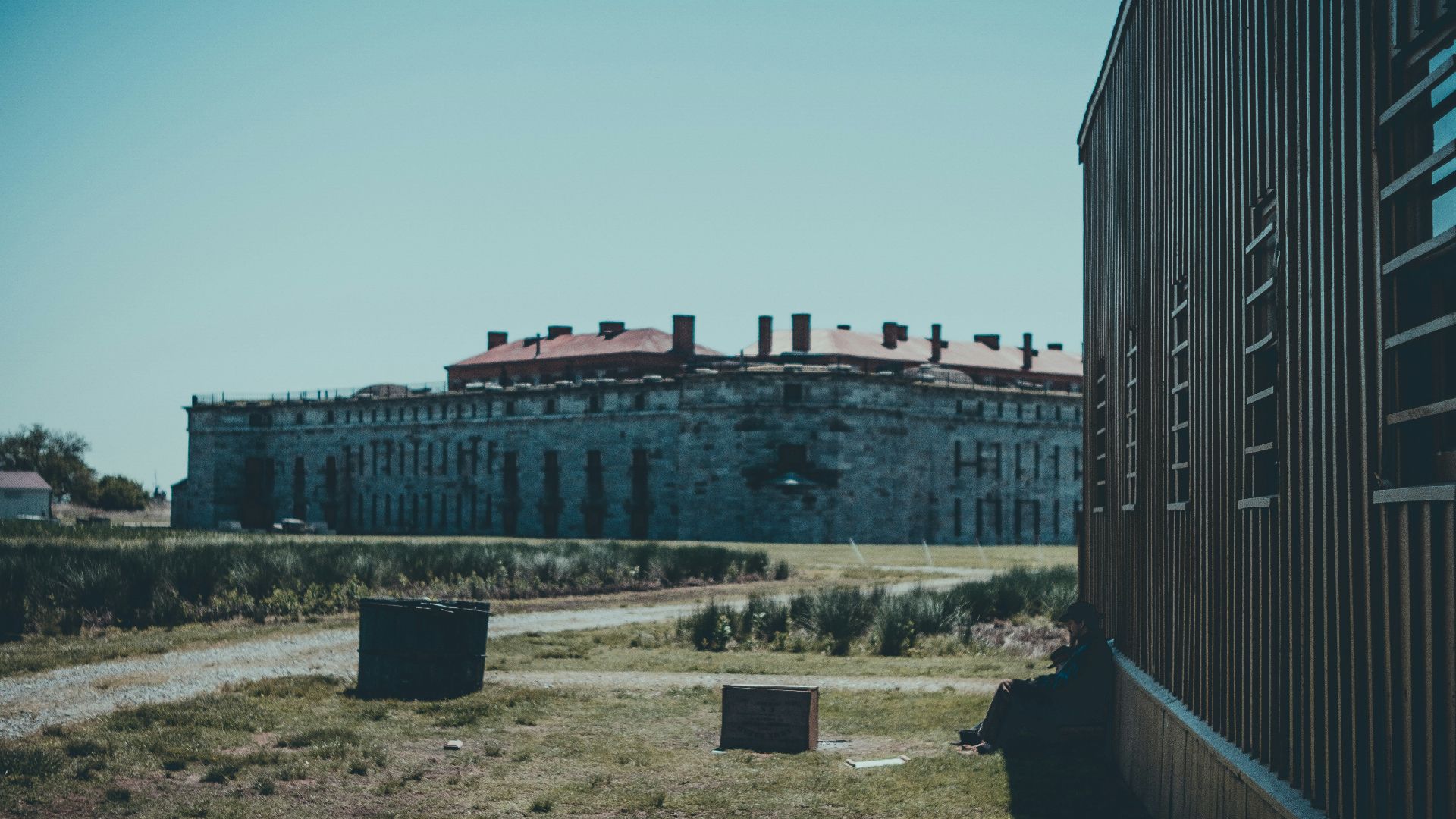 Old stone building and barn against a clear sky.