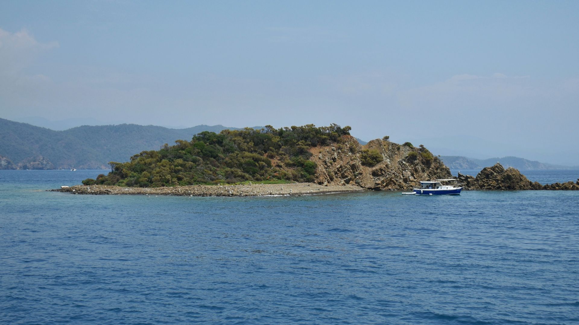 An island sits in the blue ocean waters.