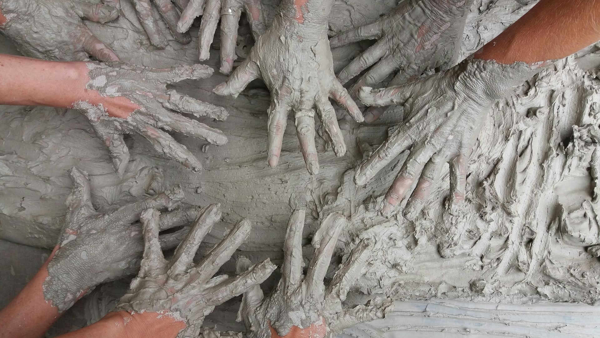 people's hand on gray mud
