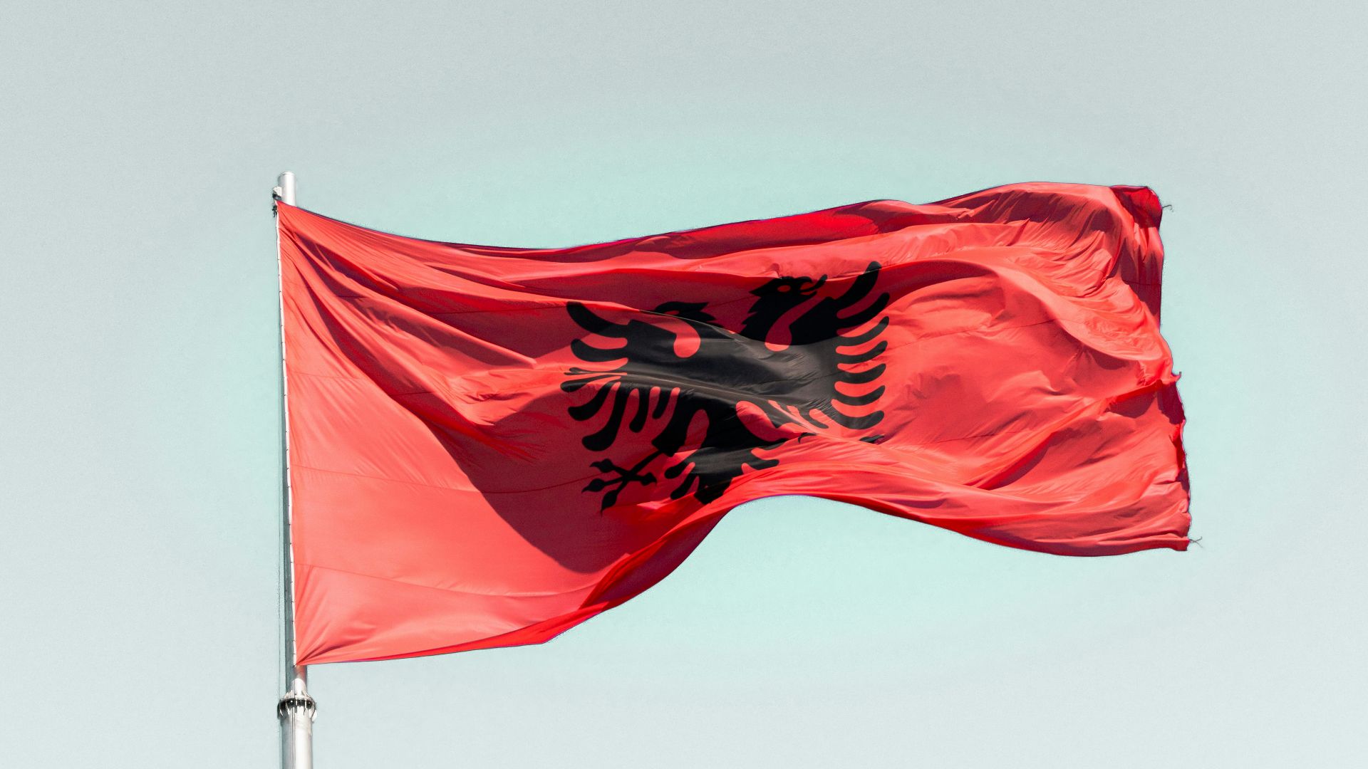 a red flag flying in the wind on a clear day