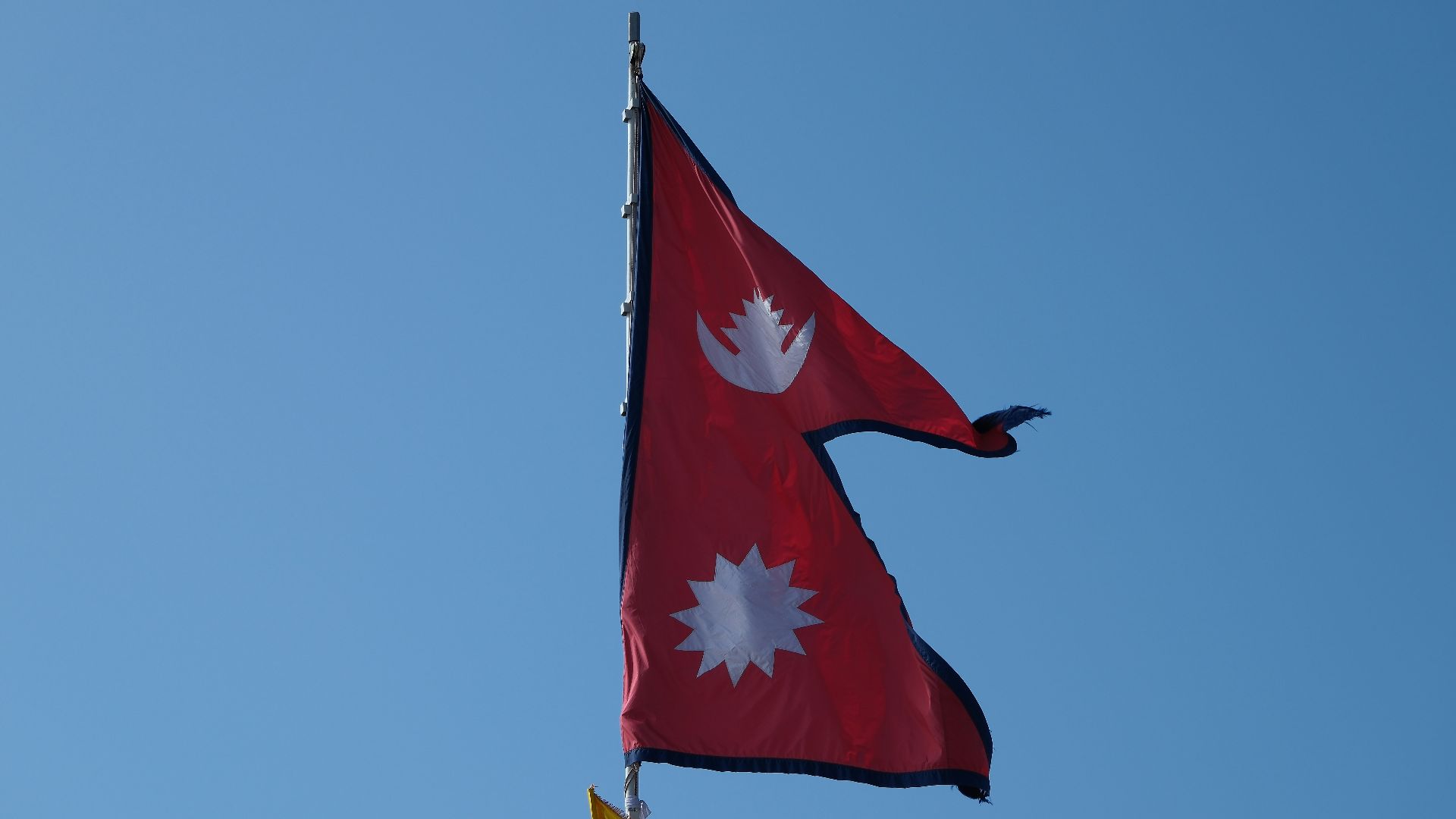 Two flags flying in the wind on a clear day