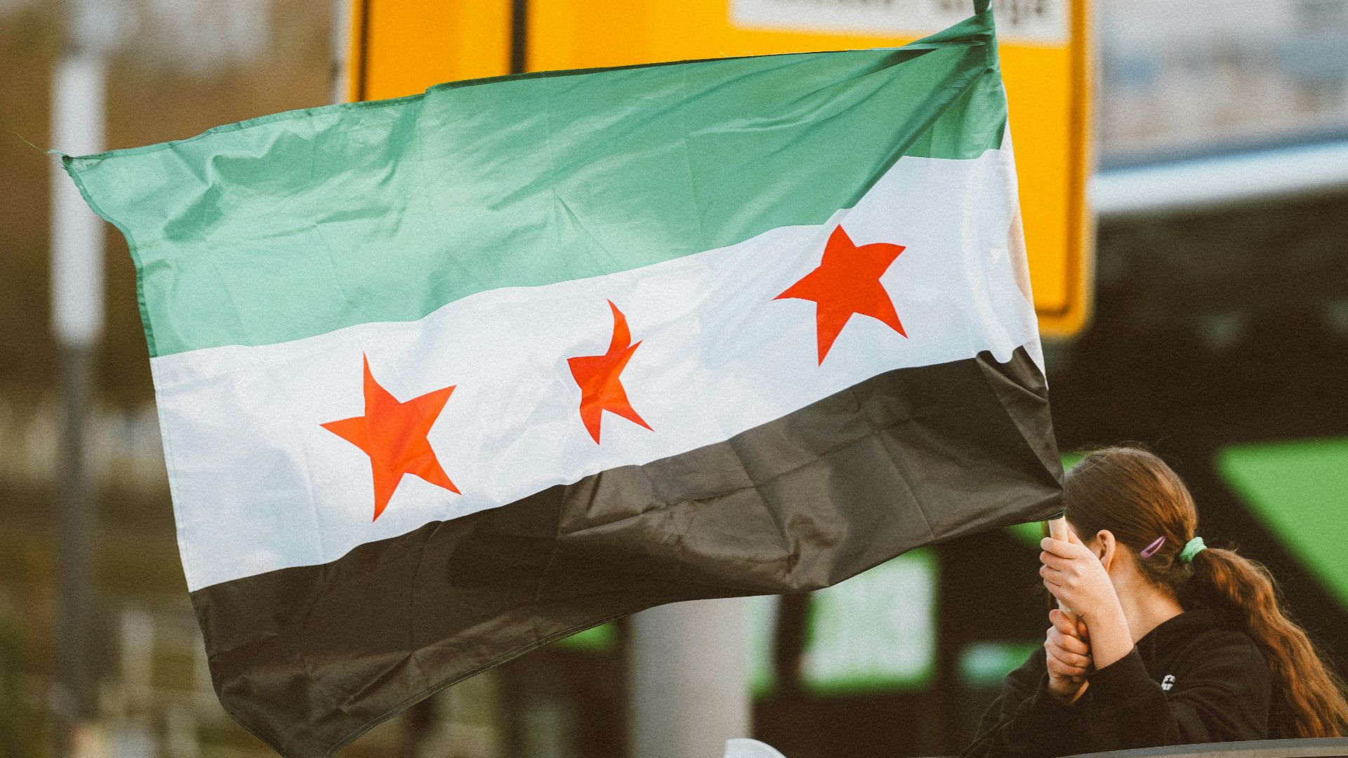 A woman holding a flag on top of a car