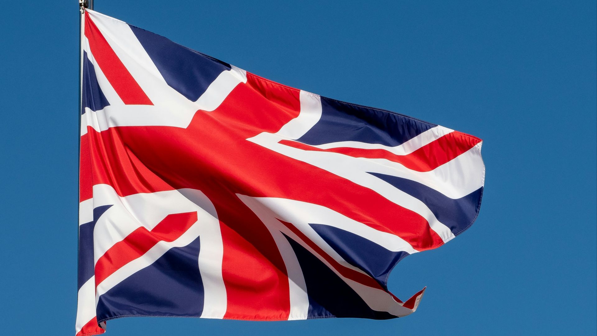 a british flag flying in the blue sky
