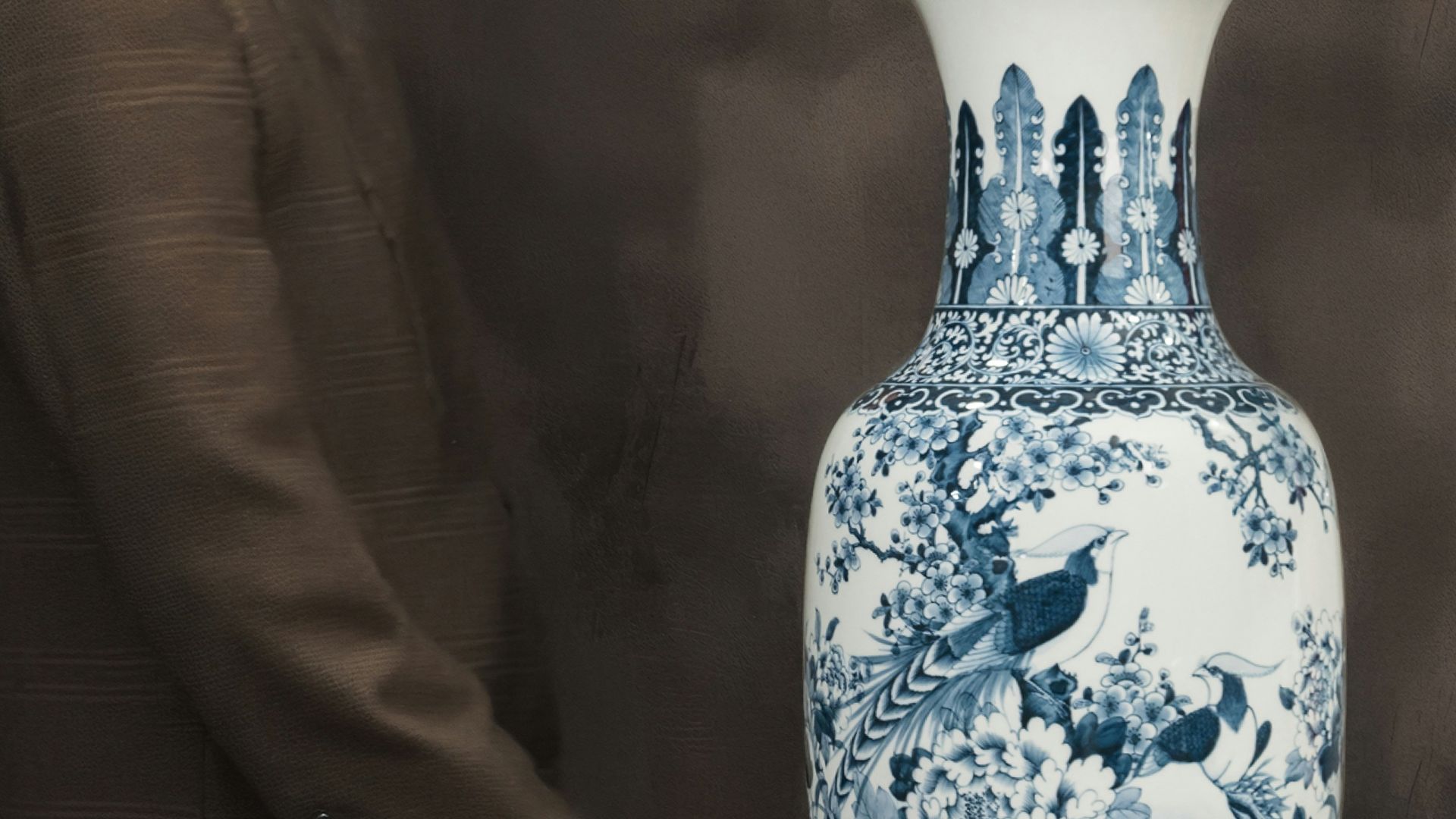 A man standing next to a large blue and white vase