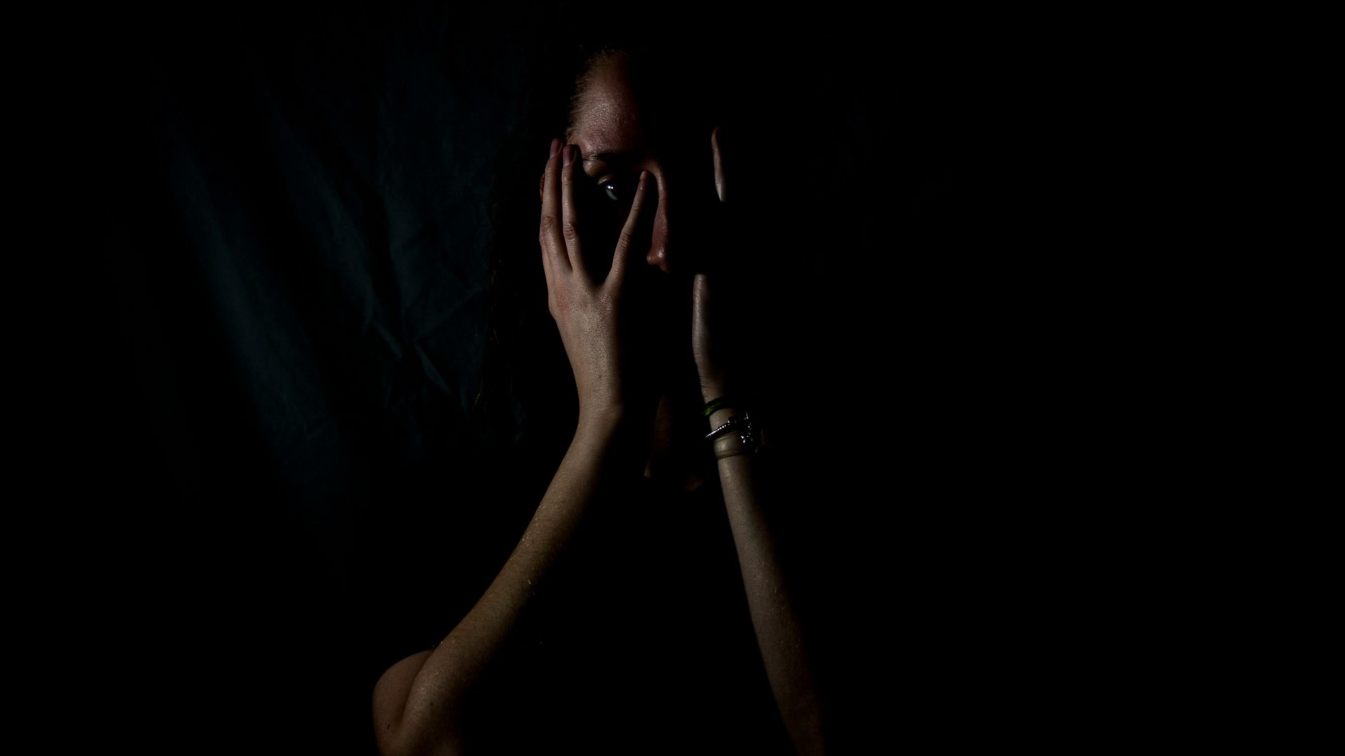 woman holding her face in dark room