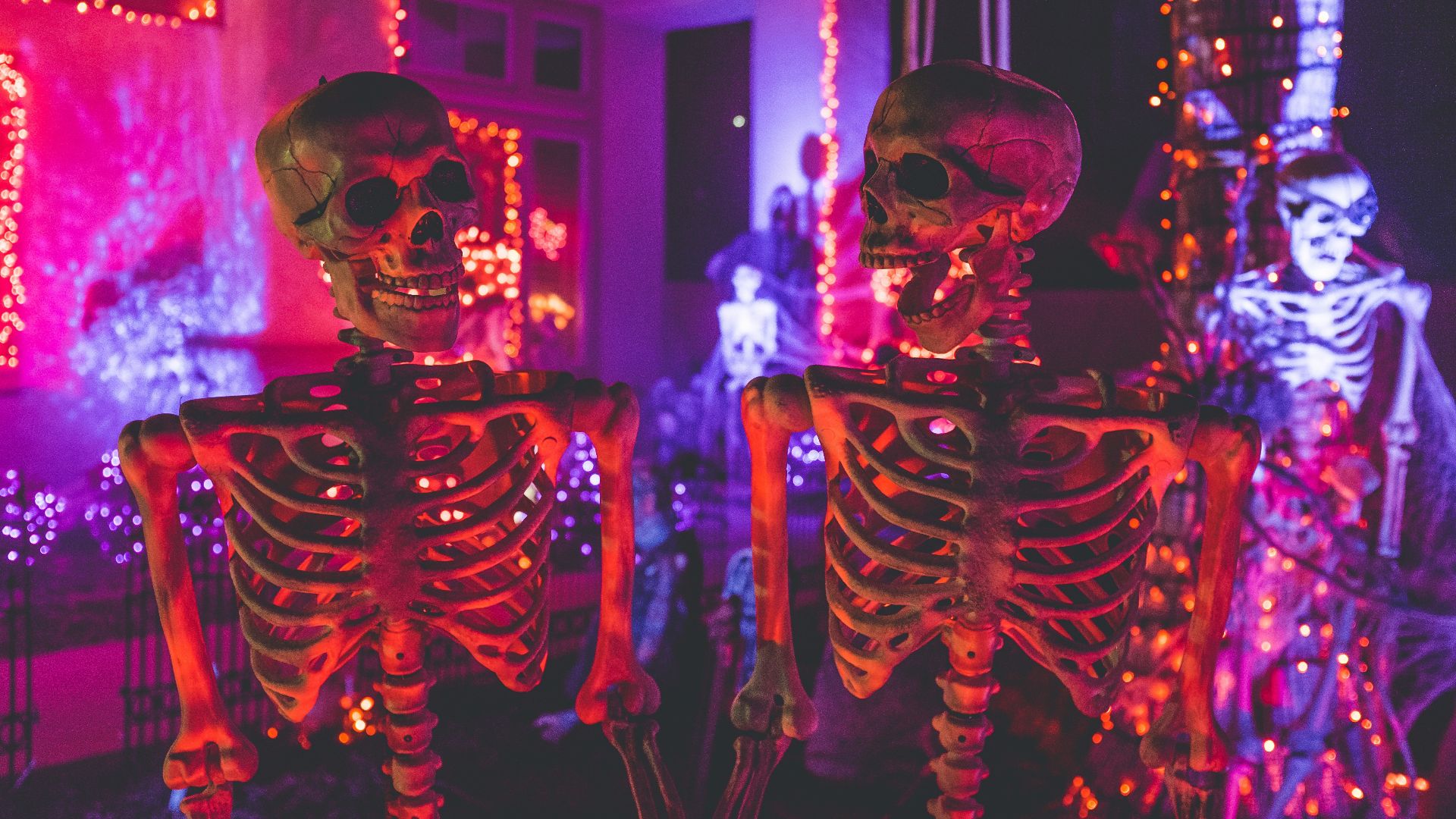 two skeleton near white concrete building with string lights at daytime