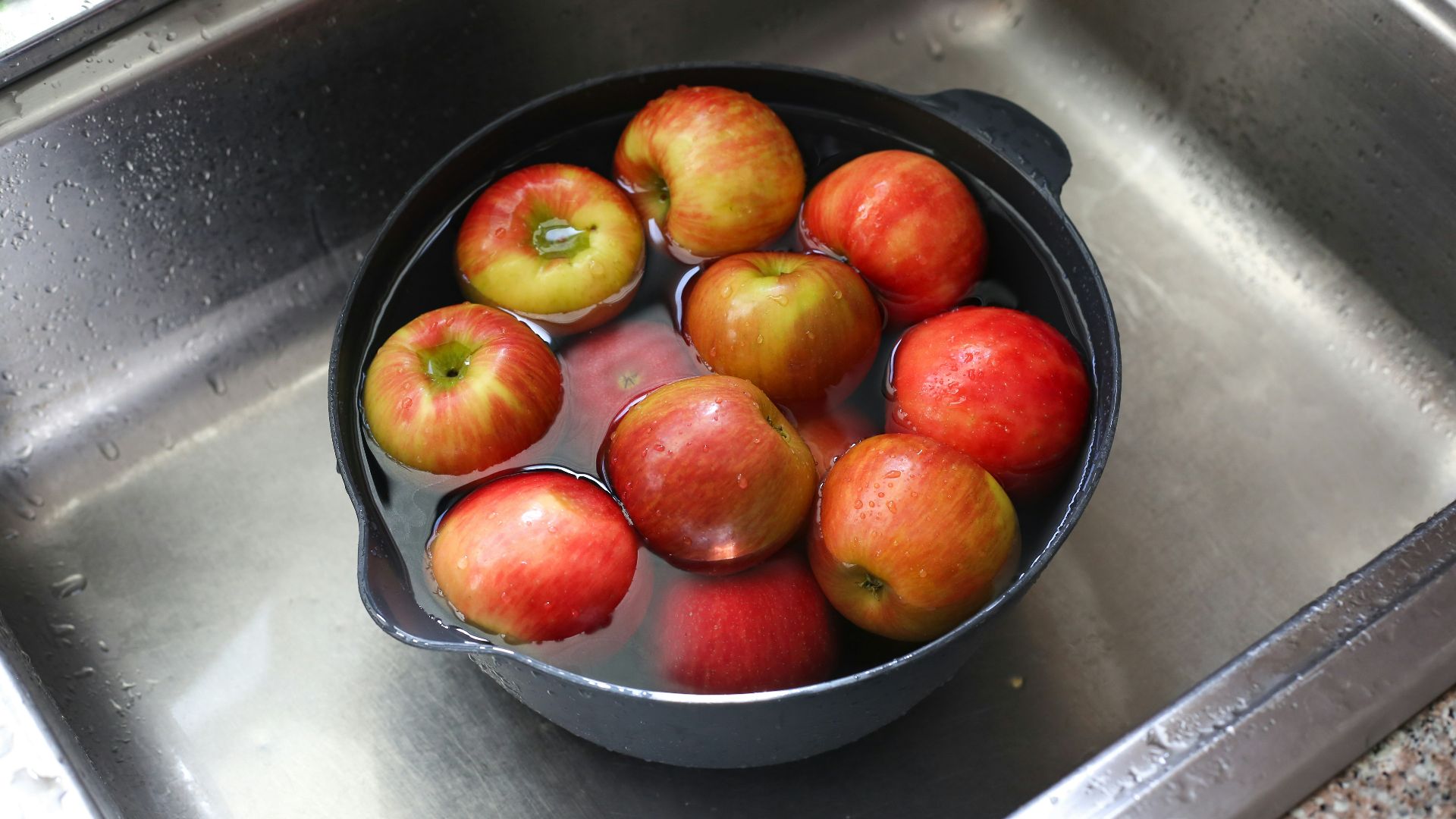 a pan filled with apples sitting on top of a sink