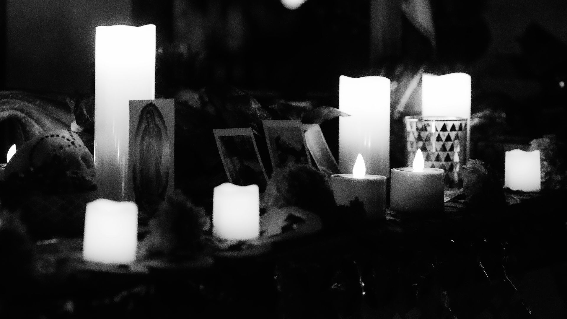 A black and white photo of candles in front of a mirror