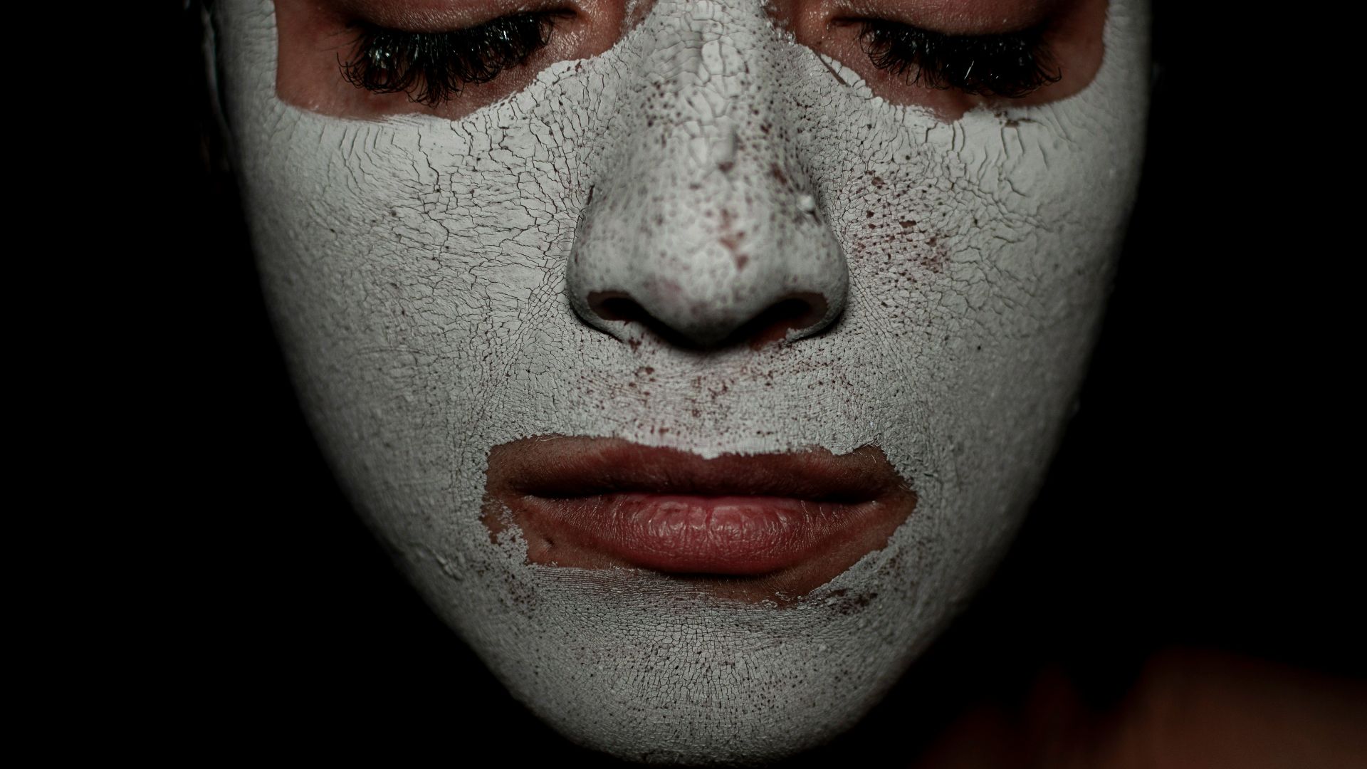 Person wearing a white face mask with closed eyes.