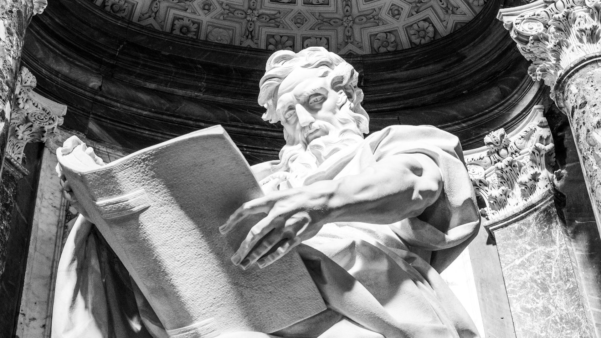 a statue of a man holding a book in front of a building