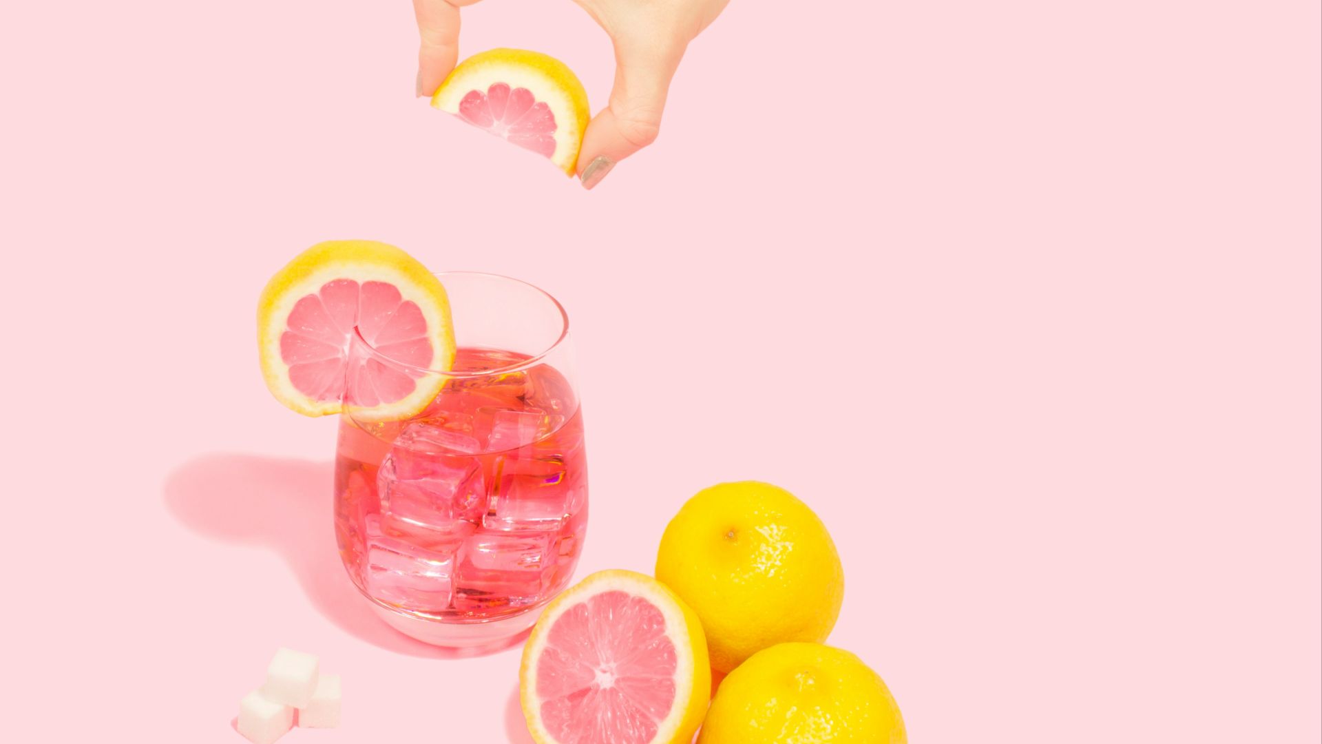 person holding slice of orange over full rock glass