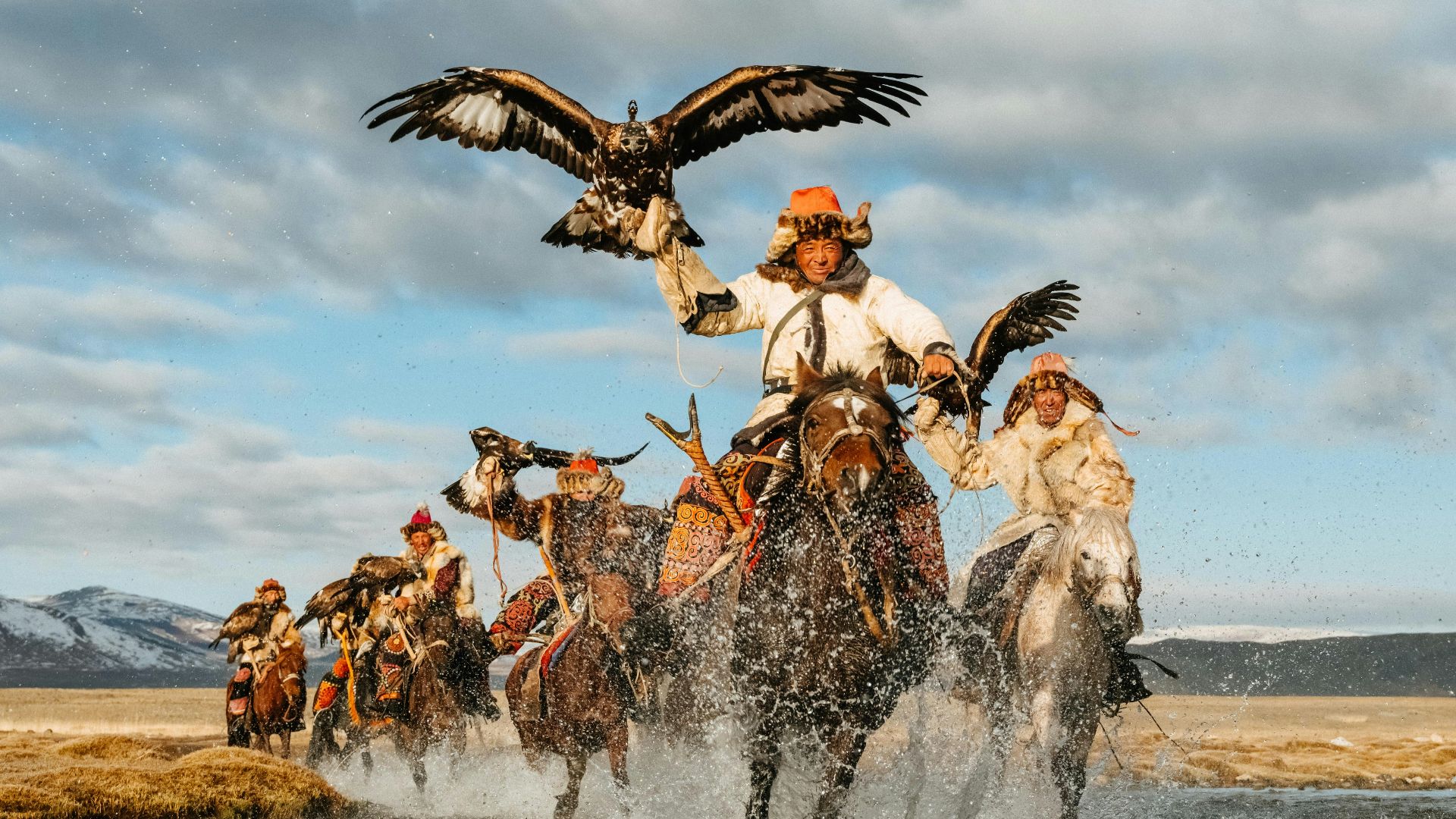 a group of people riding horses across a river