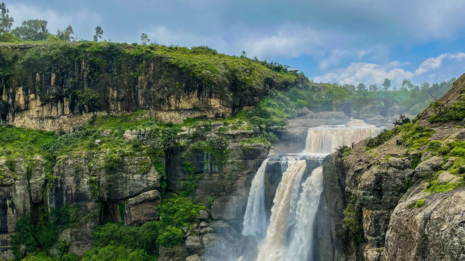 a waterfall in the middle of a lush green valley