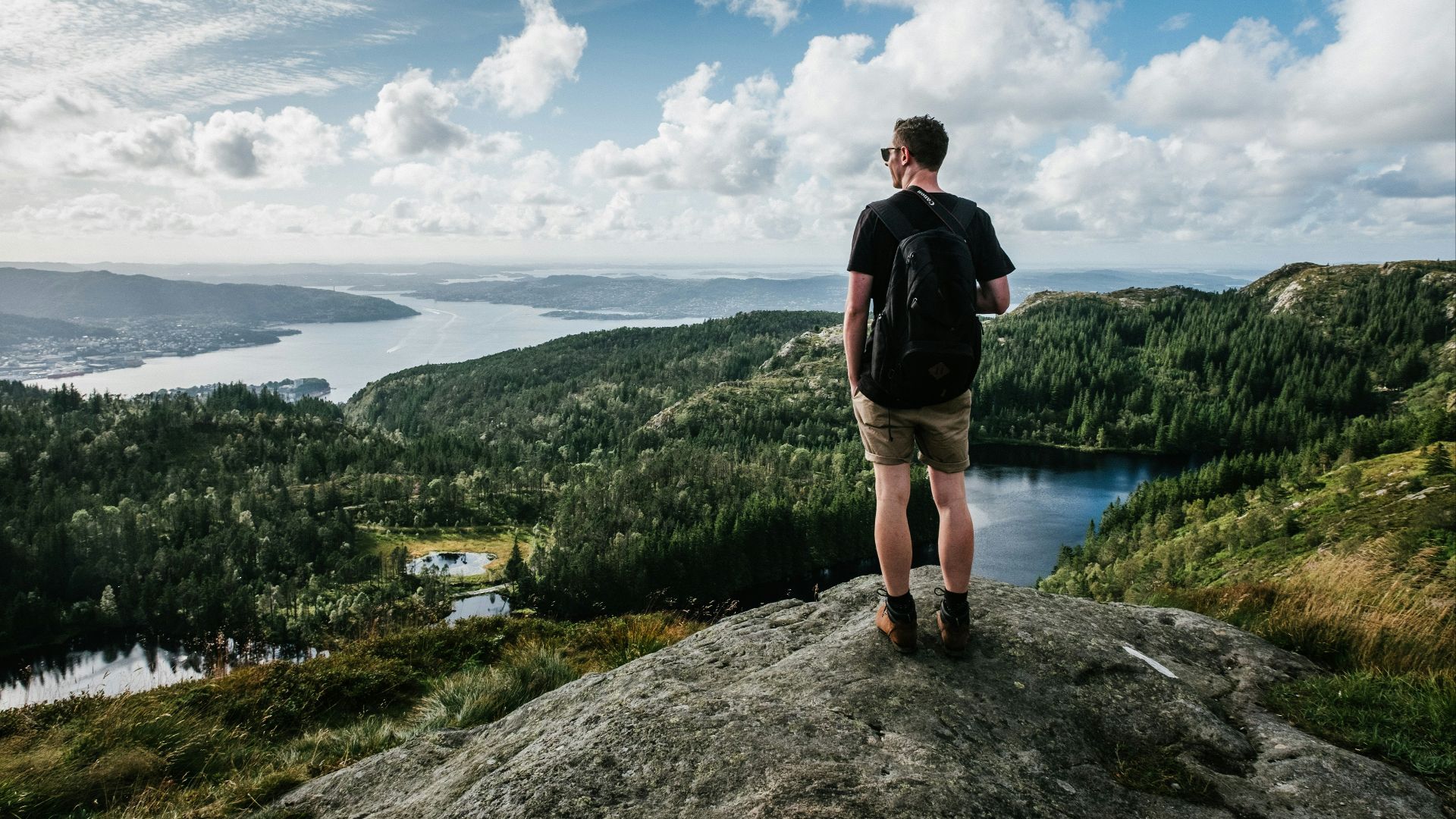 man standing on mountain beside trees
