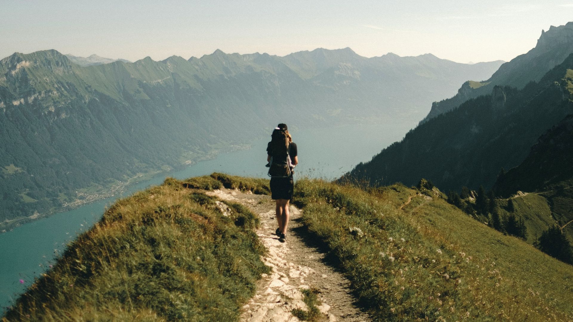 person hiking above mountain overlooking river