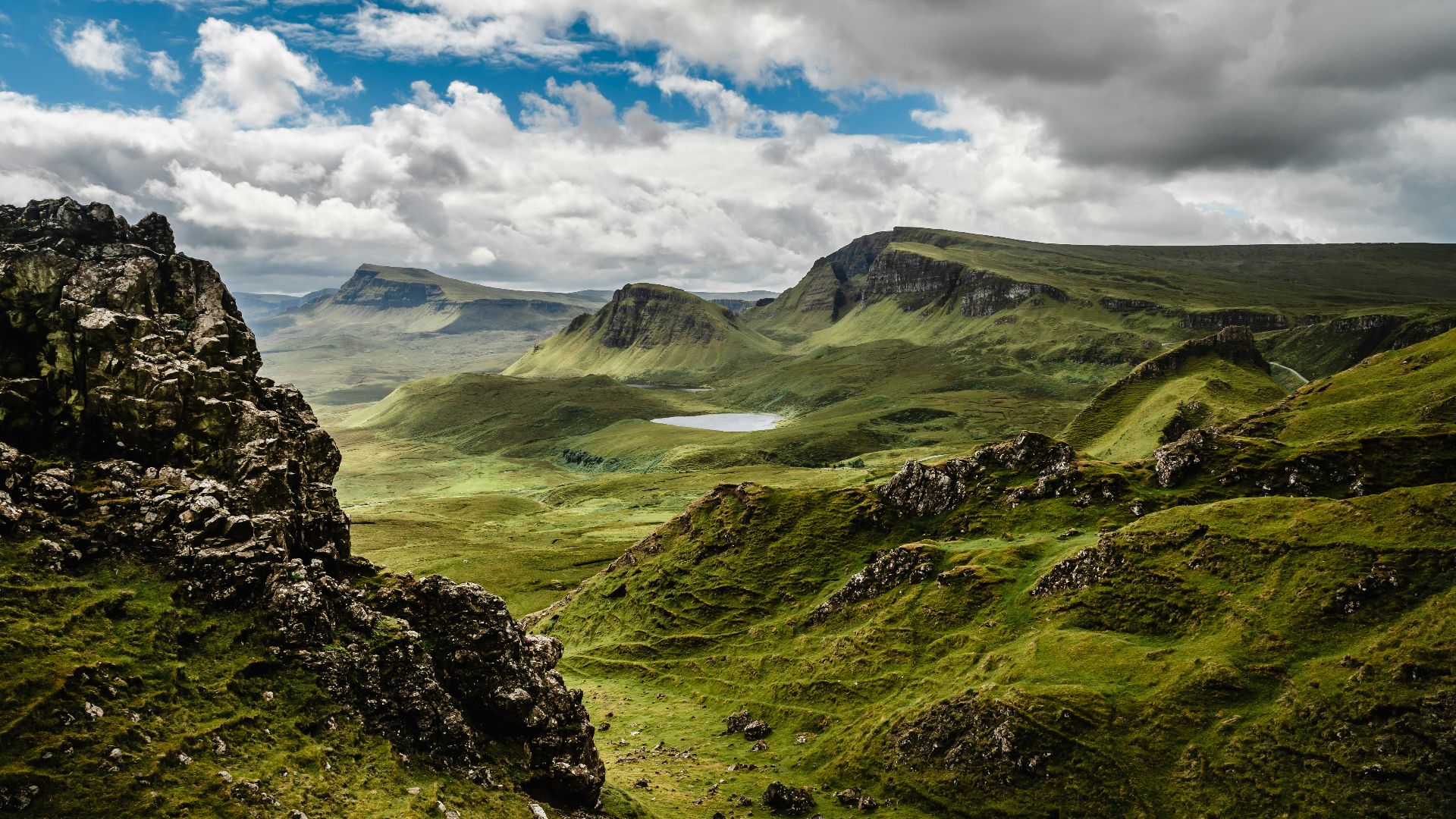 green grass on mountain under white cloudy sky