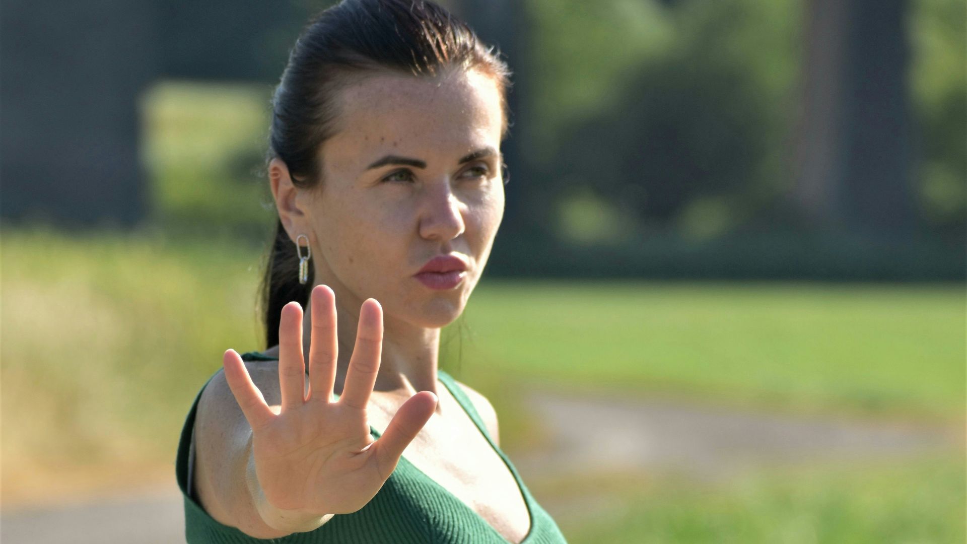 A woman in a green dress making a stop sign