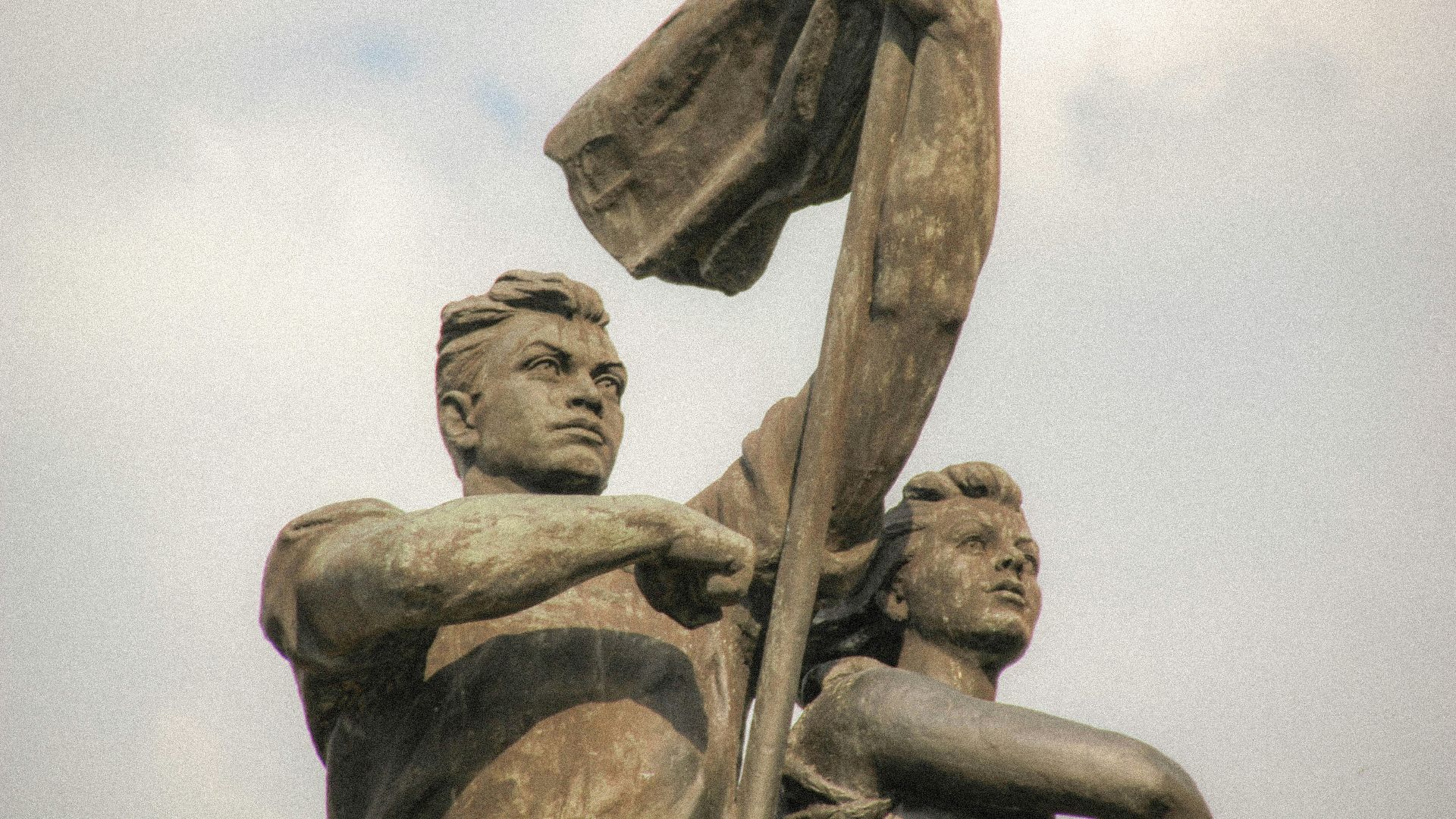 grayscale photo of man holding stick statue