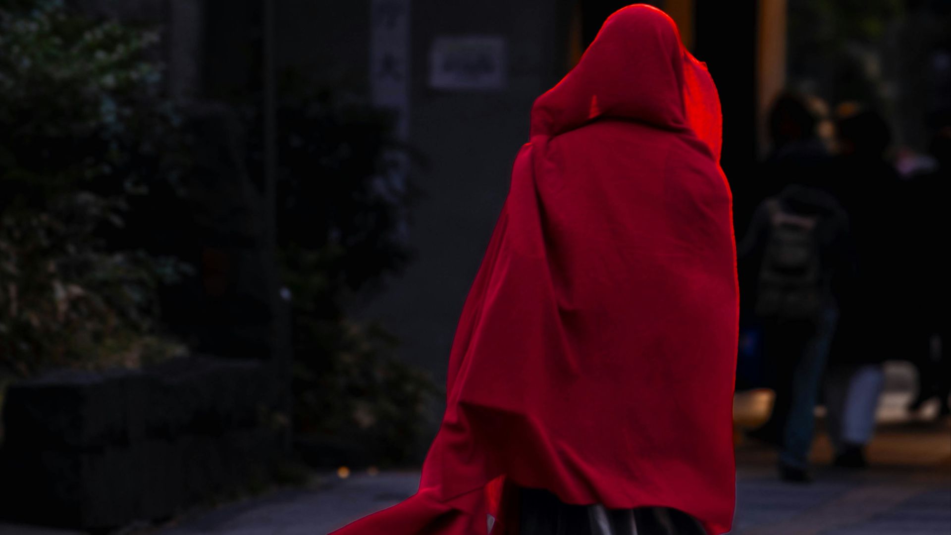 a person in a red cloak walking down a street
