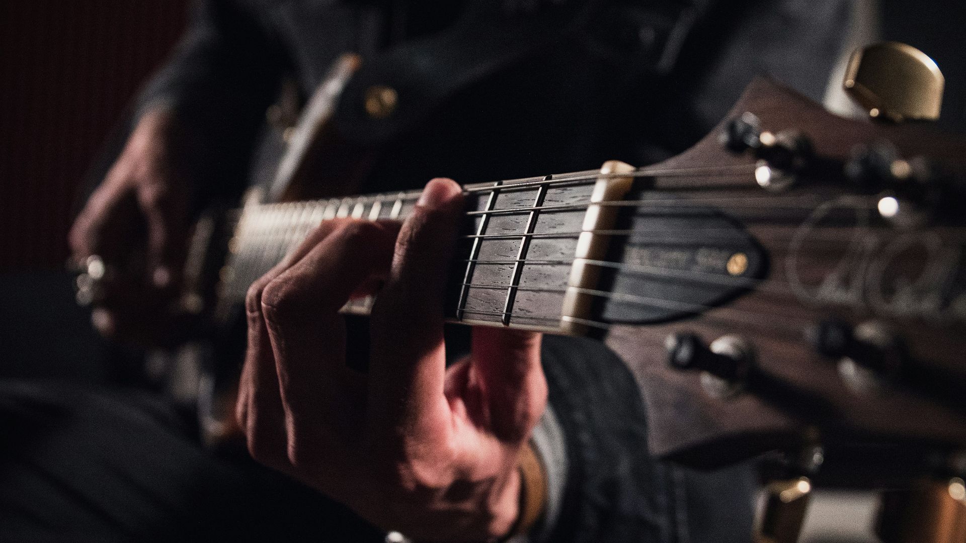 man in black jacket playing guitar