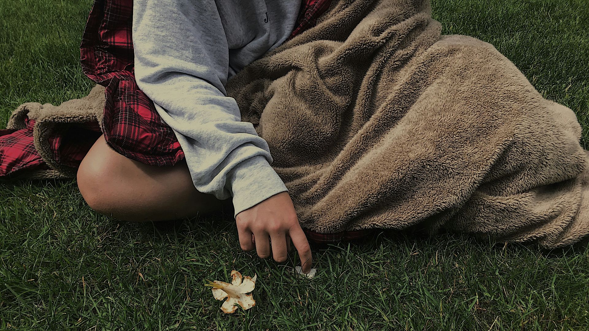 person in gray jacket lying on green grass field