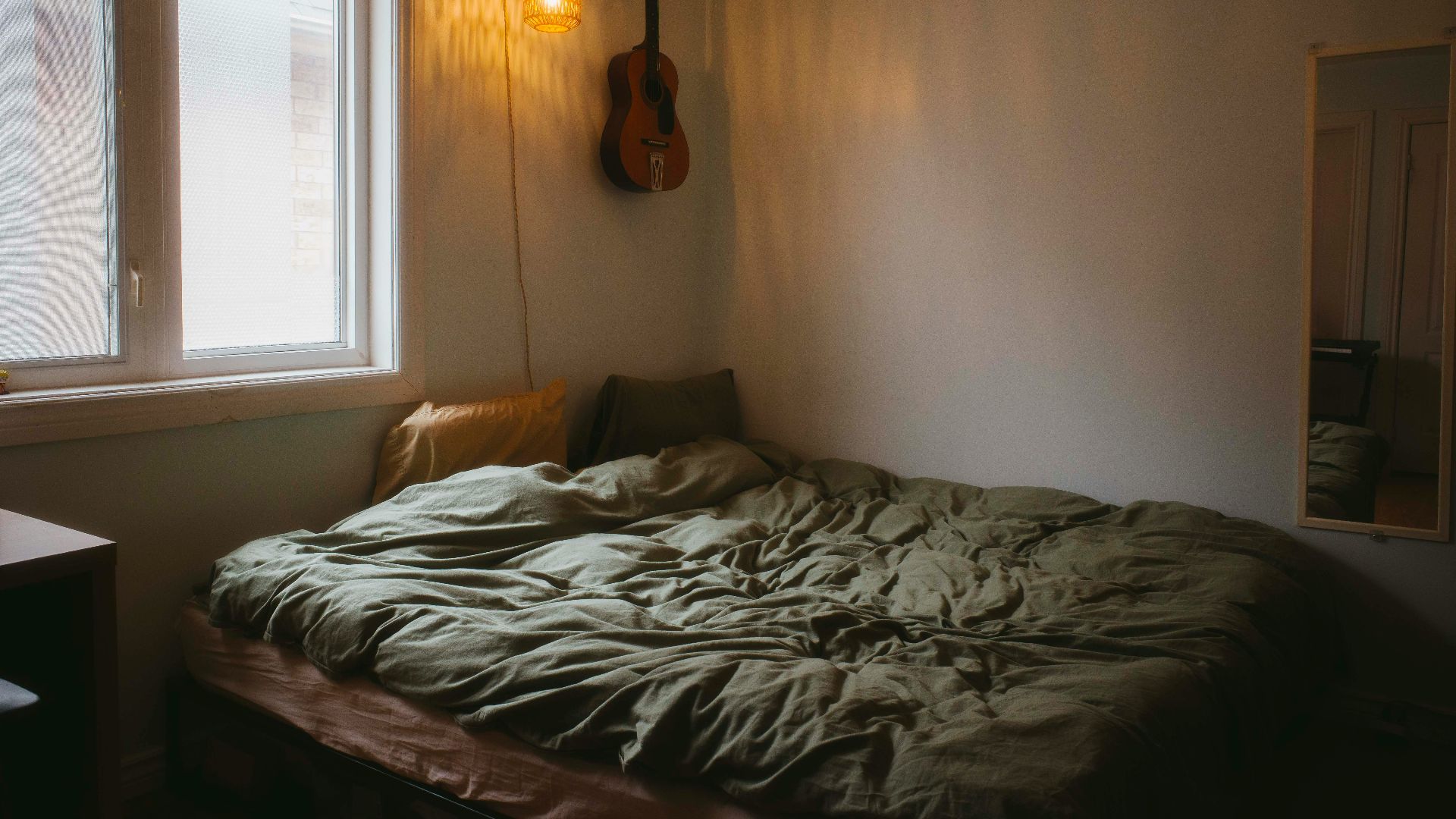 A cozy bedroom with a guitar and bed.