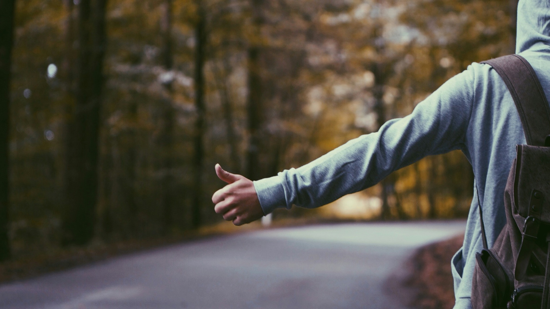 person standing beside road doing handsign