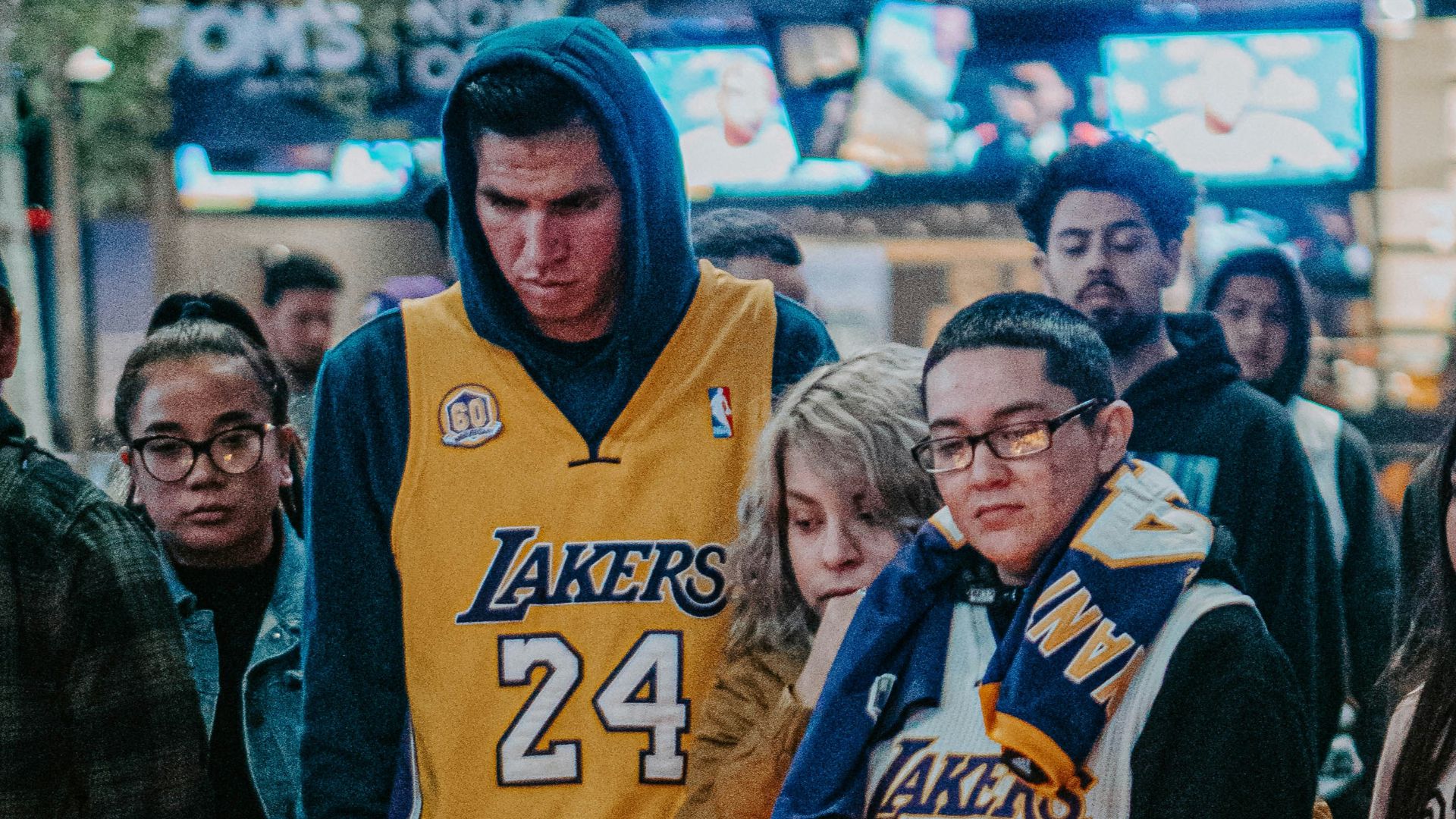 man in blue and white nike jersey shirt standing beside woman in black jacket