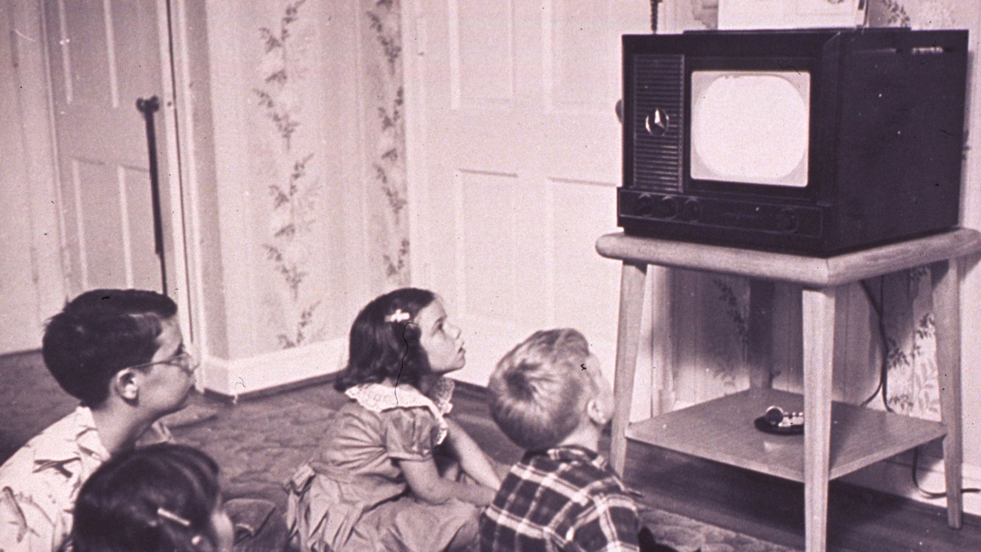 a group of children sitting on the floor in front of a tv