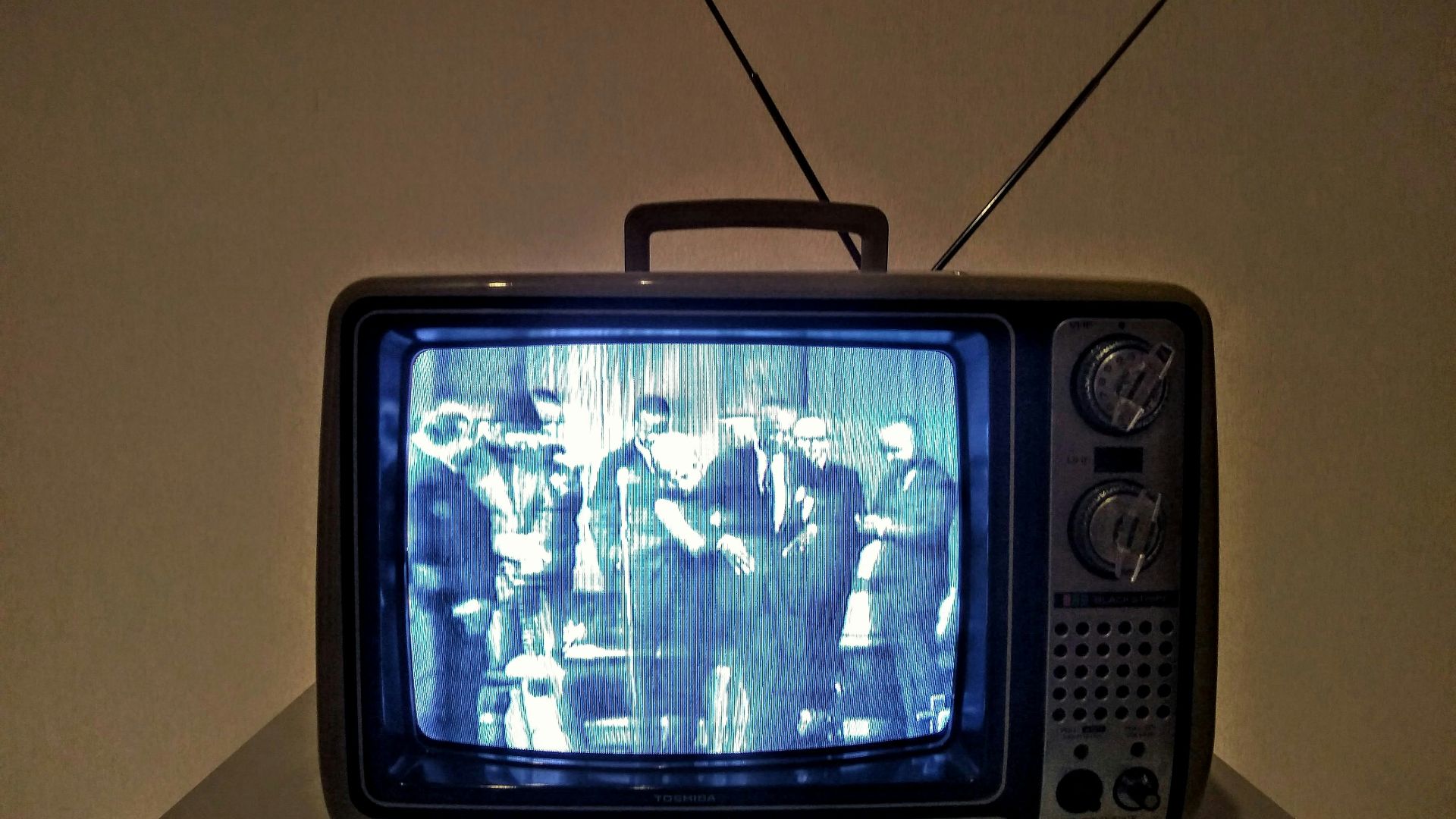 black crt tv turned on on white table