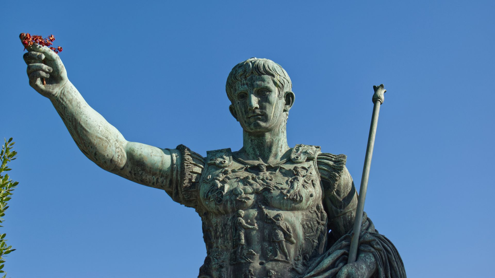 man holding stick statue under blue sky during daytime