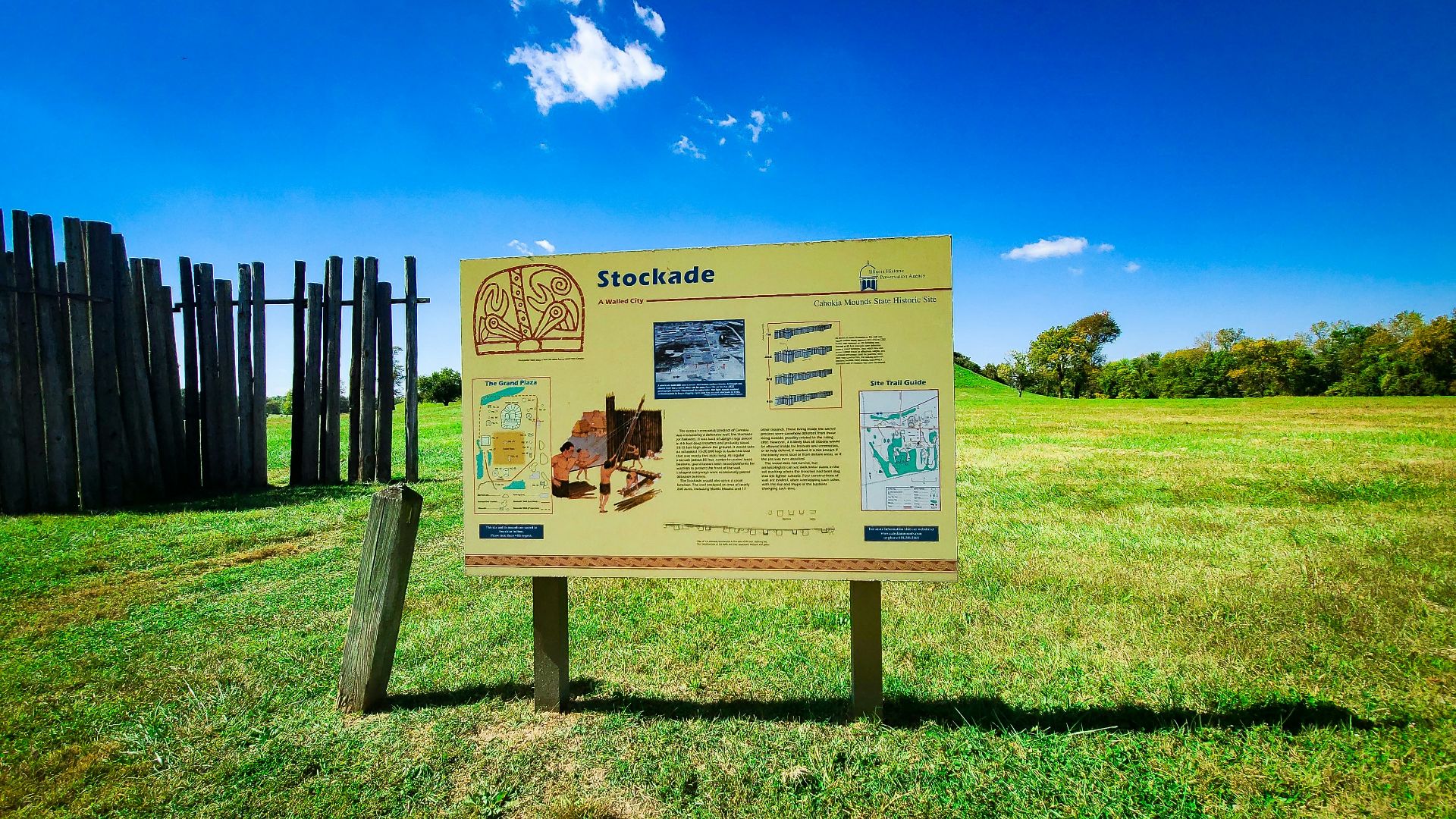 a sign in a grassy field with a fence in the background