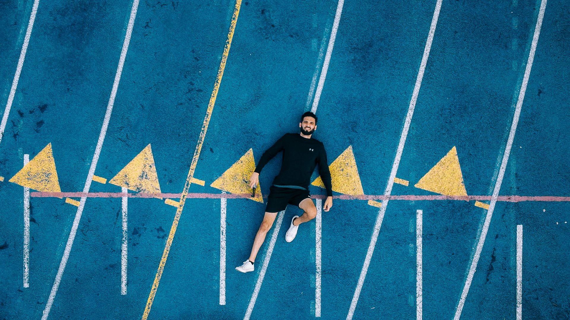 man in black jacket and blue pants standing on blue and white floor