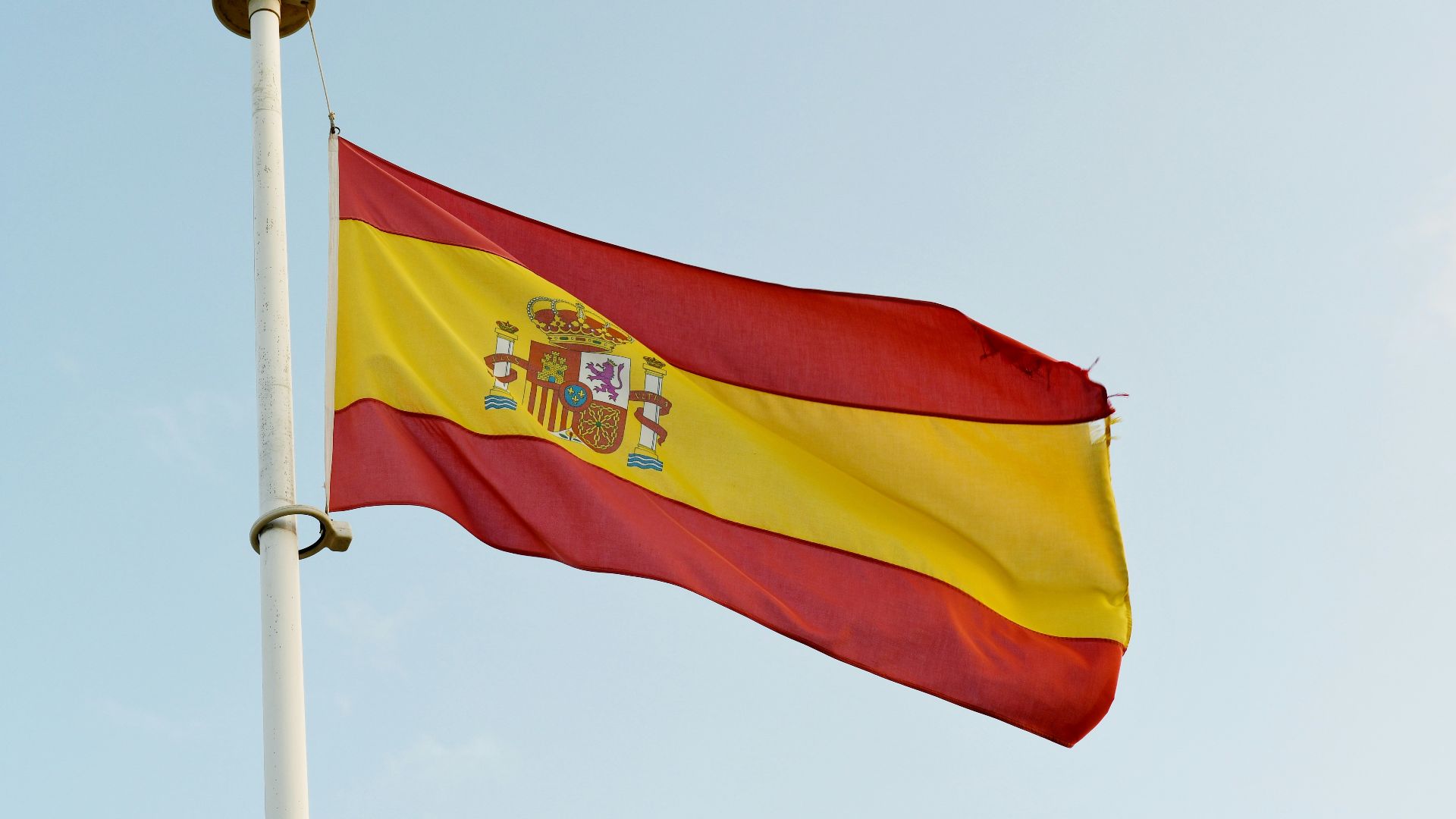 the spanish flag is flying high in the sky