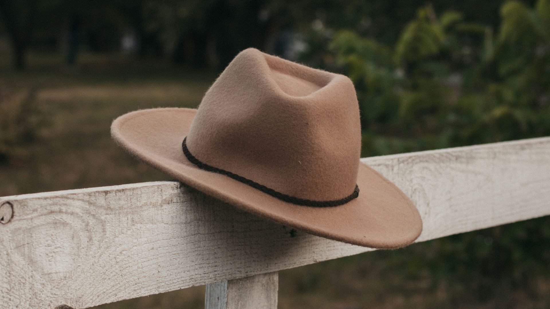 brown cowboy hat on wooden fence