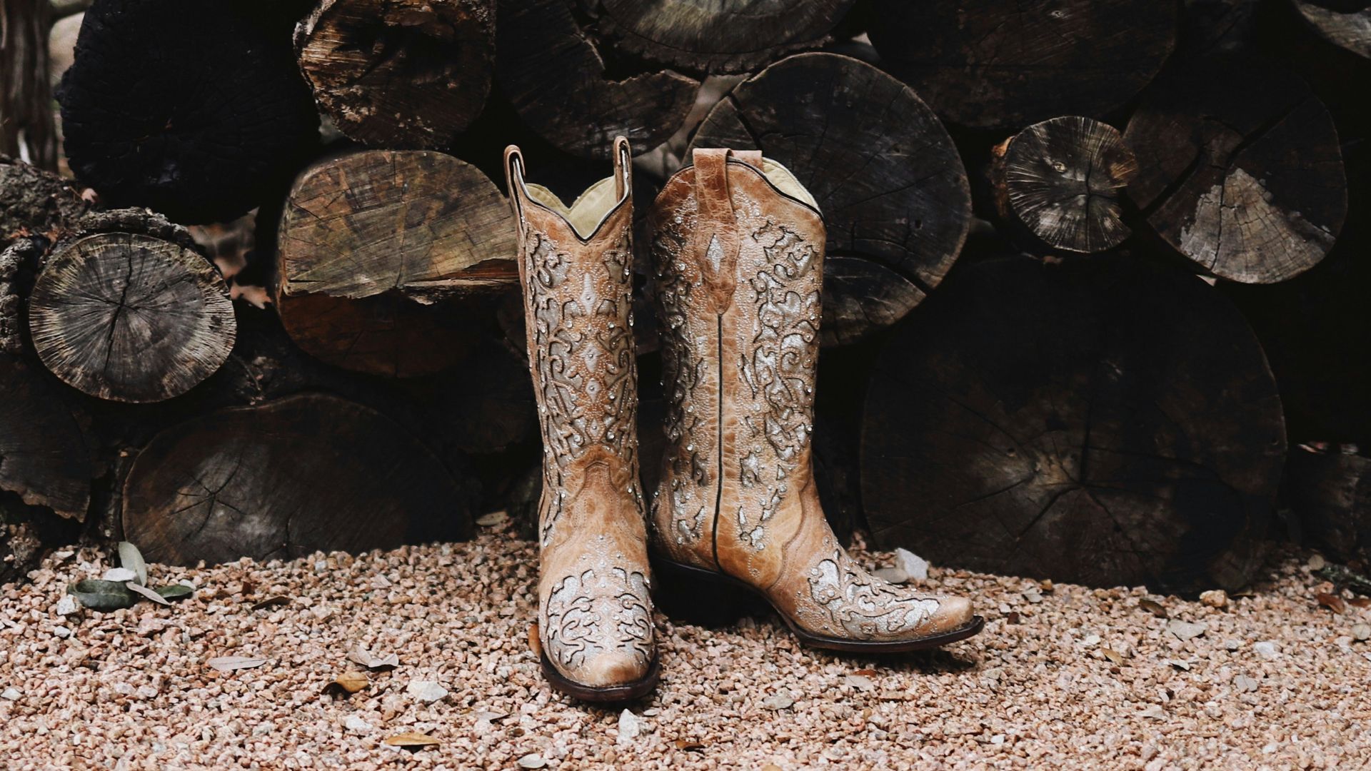 pair of brown leather cowboy boots near firewood