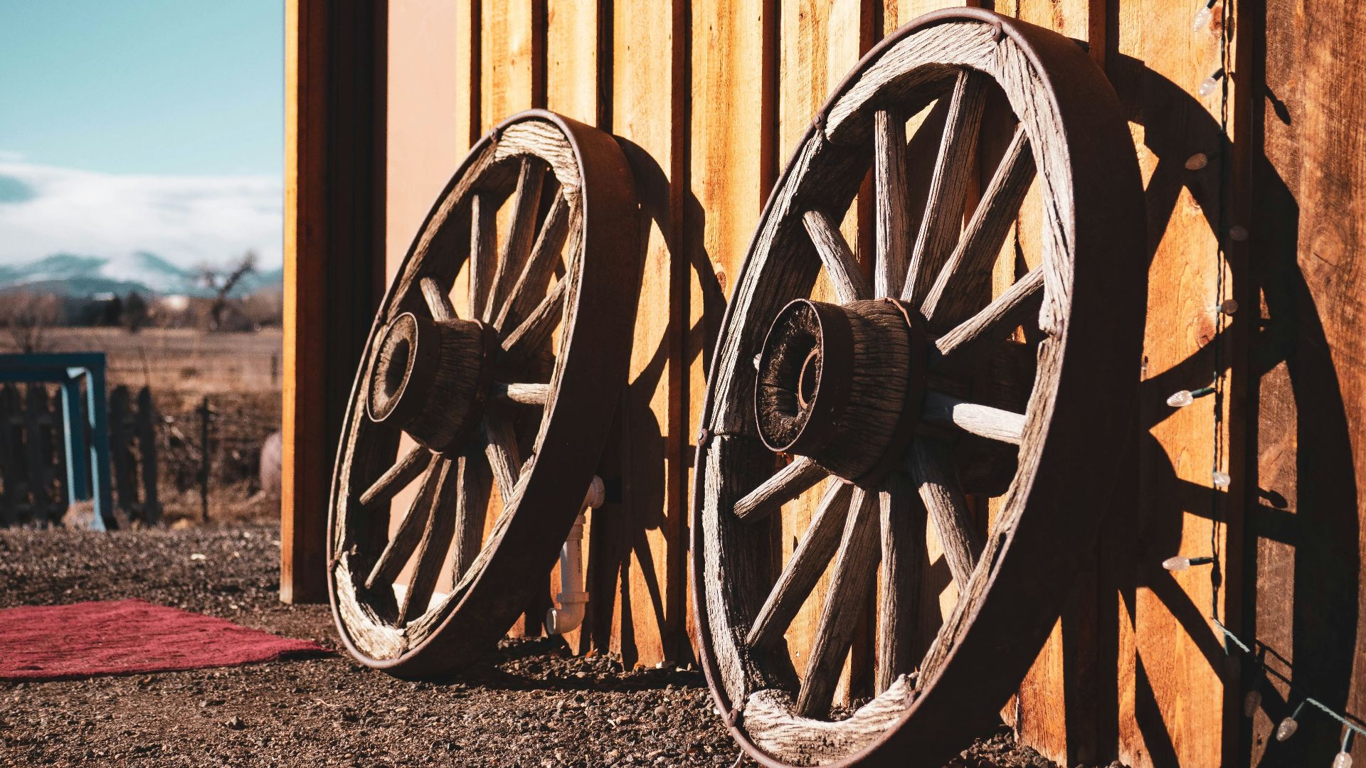 two brown carriage wheels learning on brown house