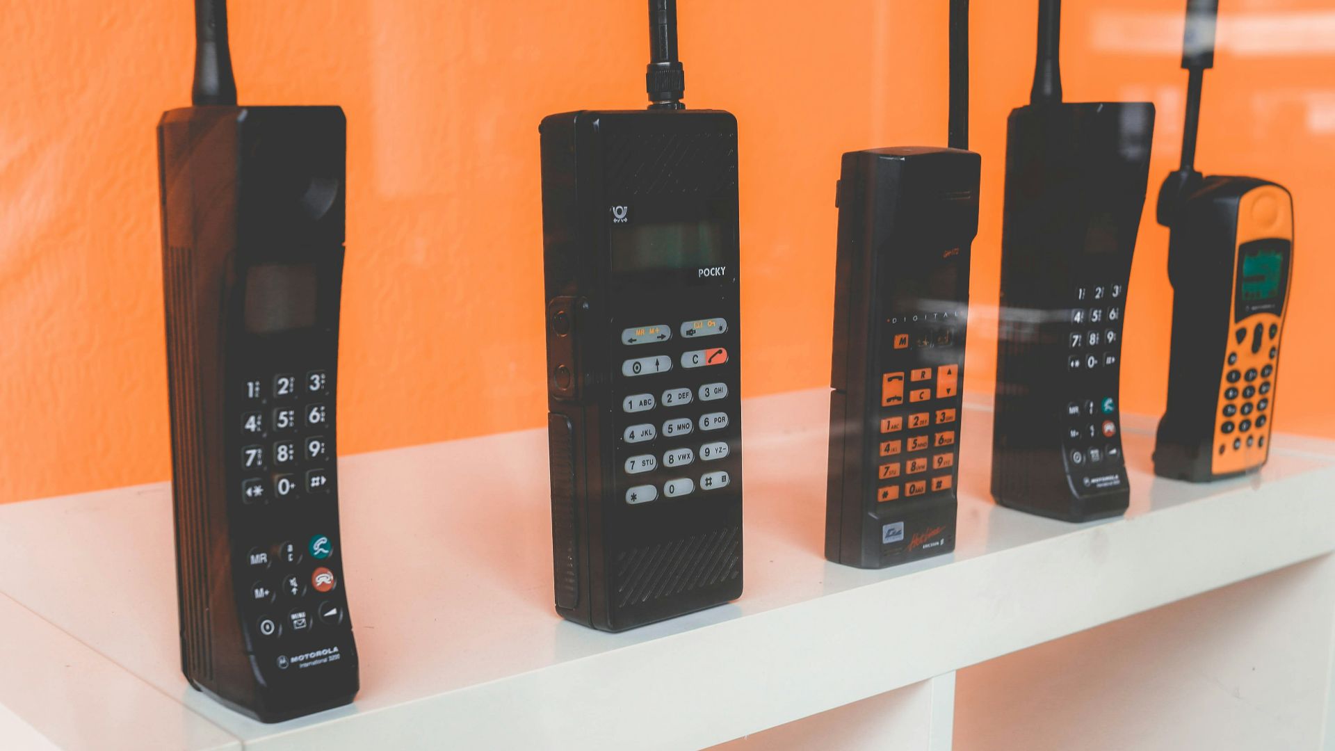 five assorted-brand wireless phones on desk