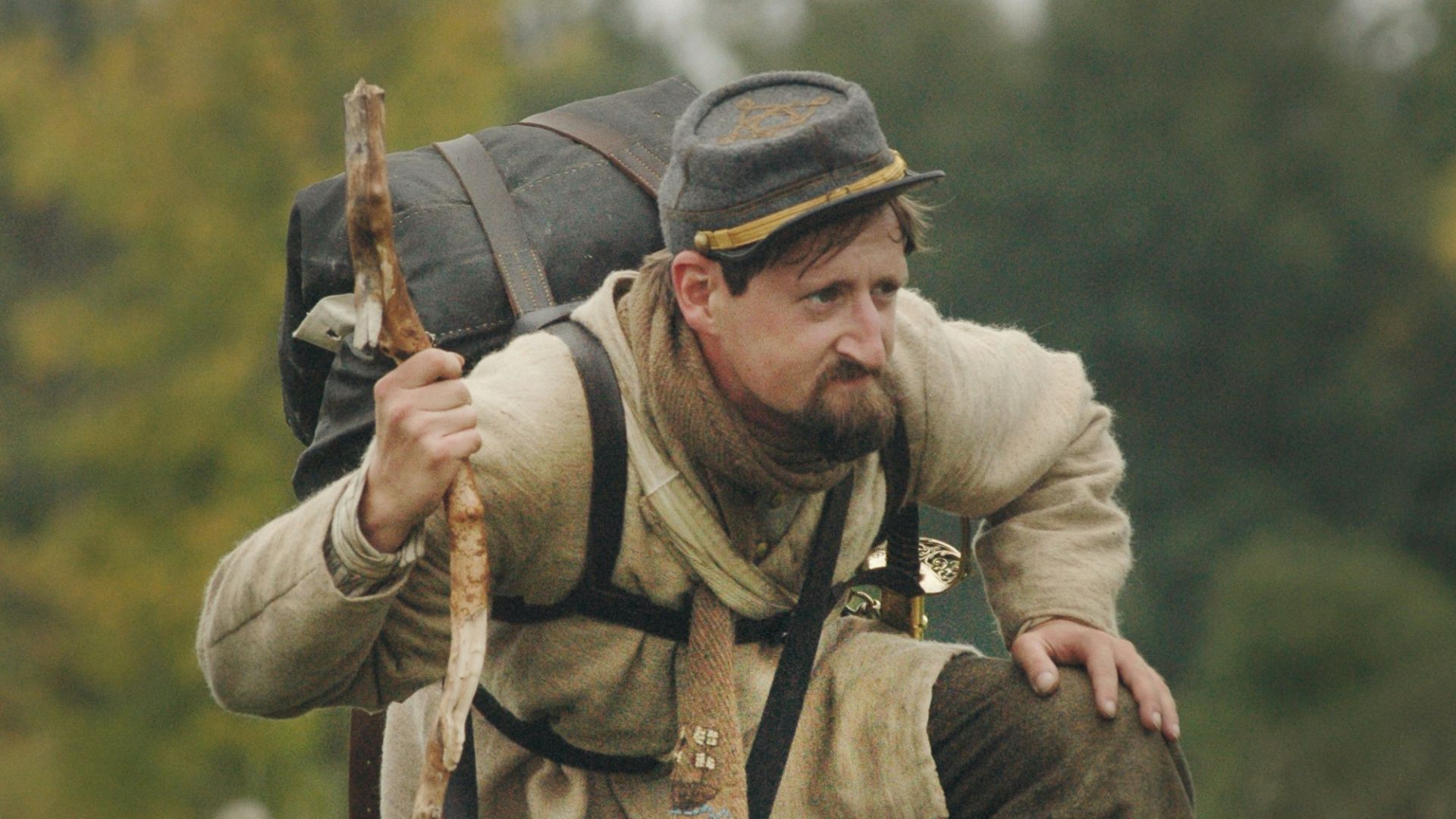 man carrying backpack and kneeling on grass field during daytime