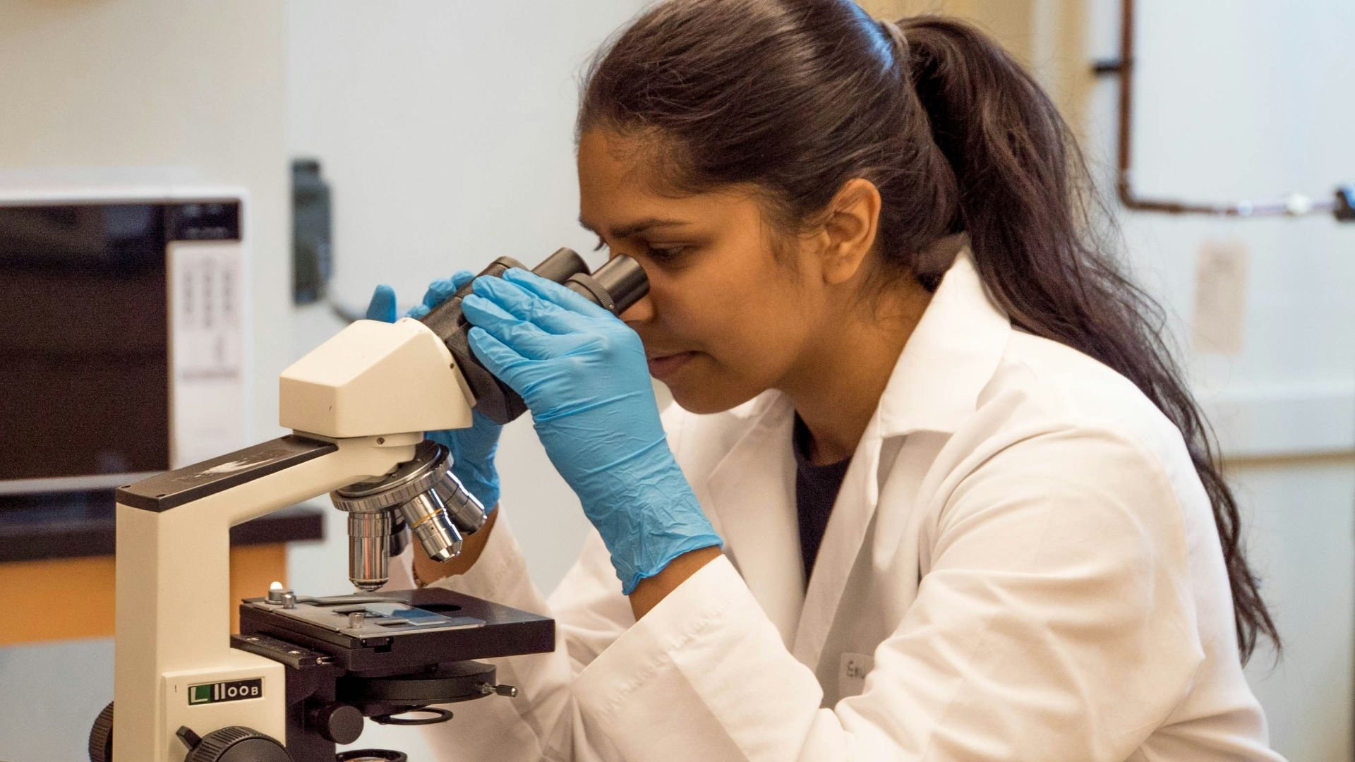 woman looking on microscope inside room