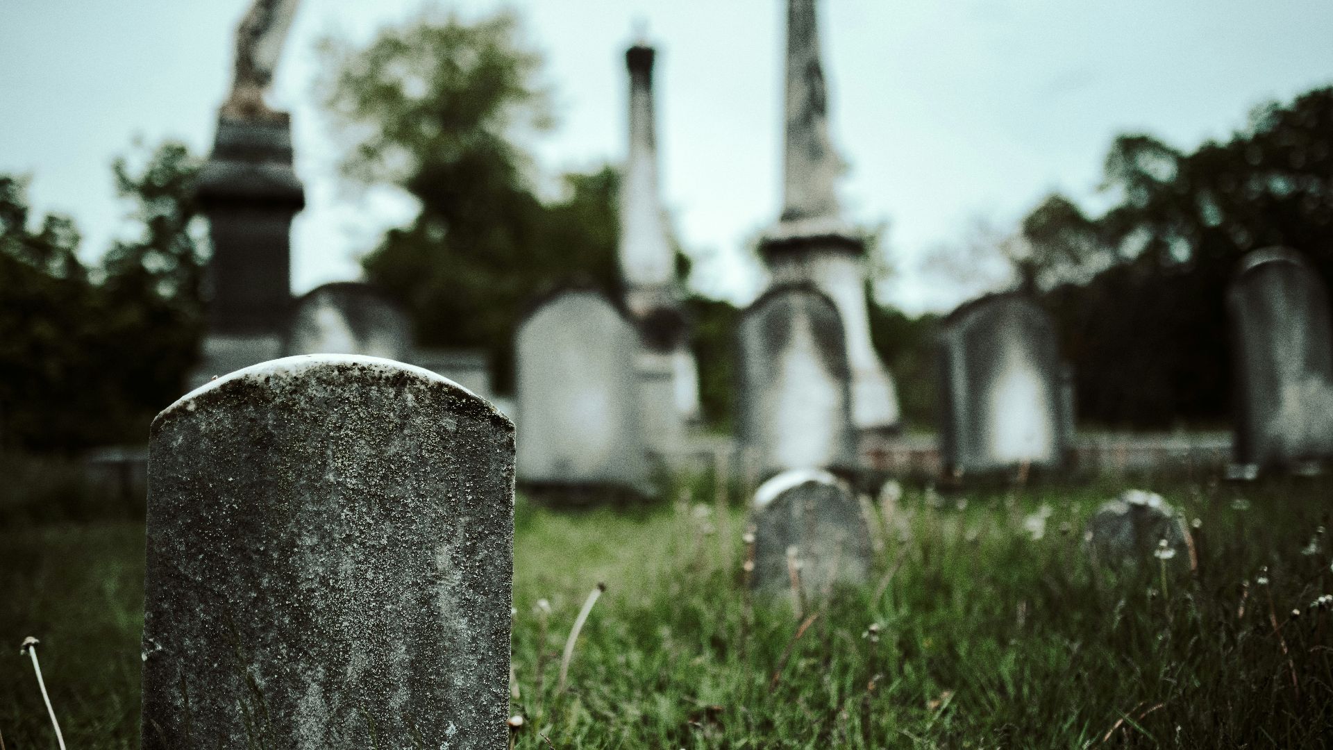 gray concrete cross on green grass field during daytime