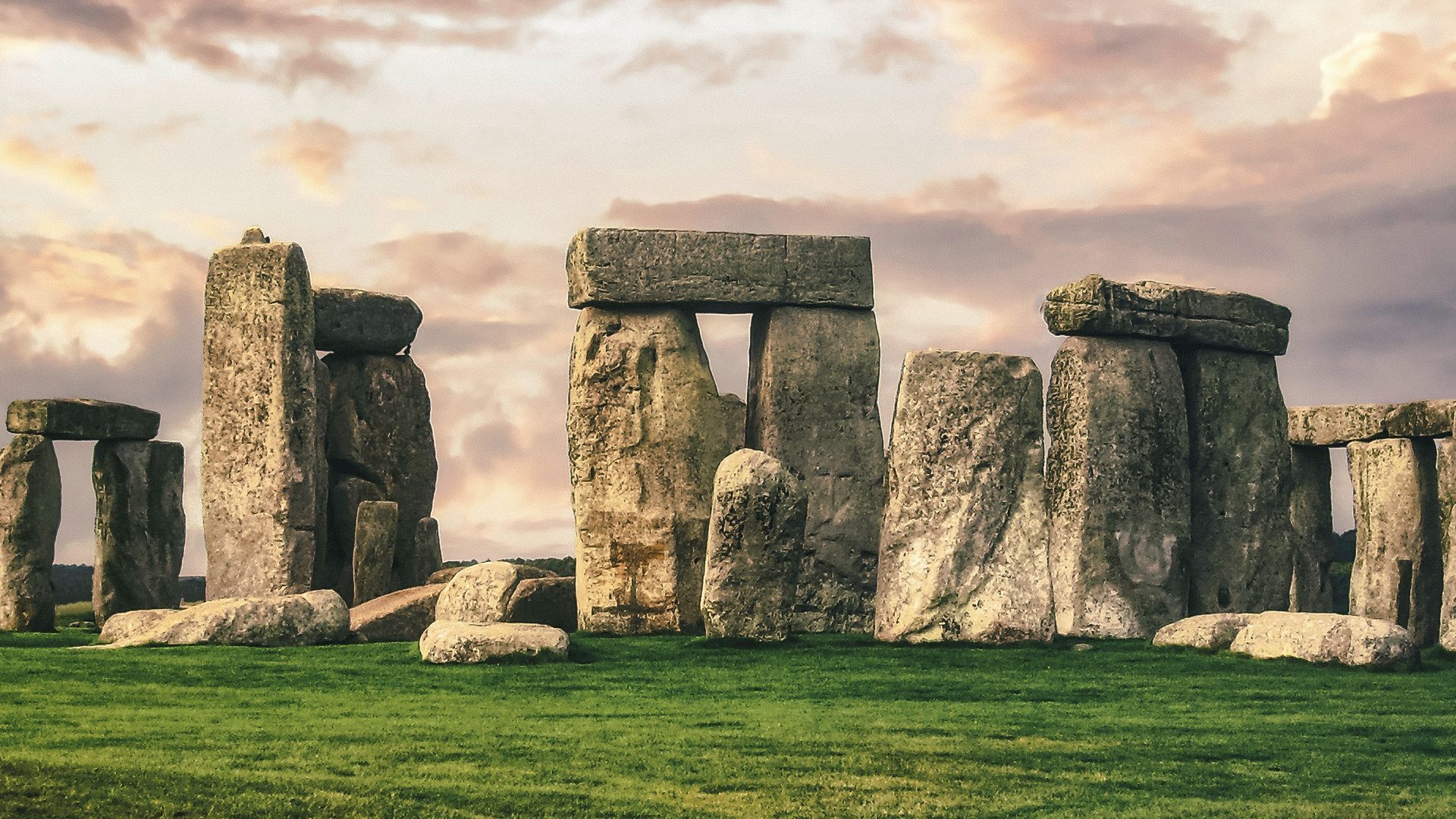 gray rock formation on green grass field under gray cloudy sky