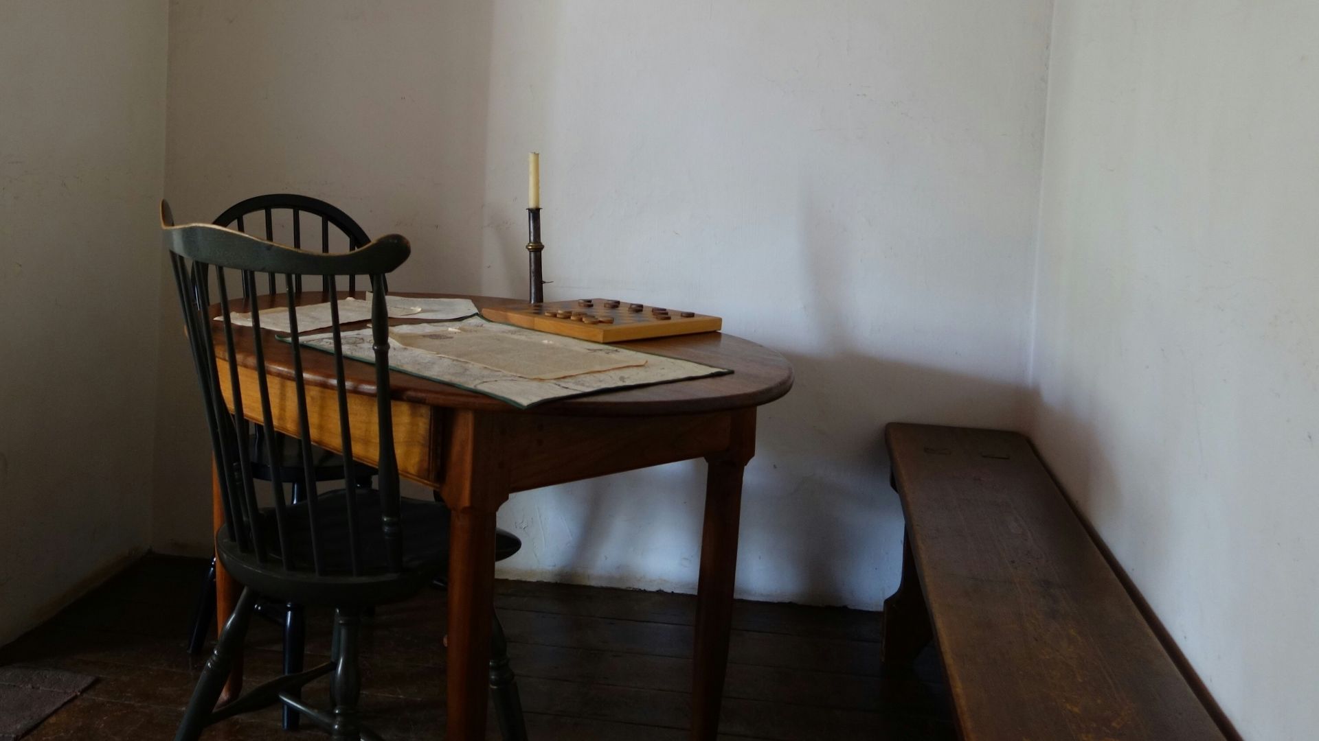round brown wooden table and two black windsor chairs